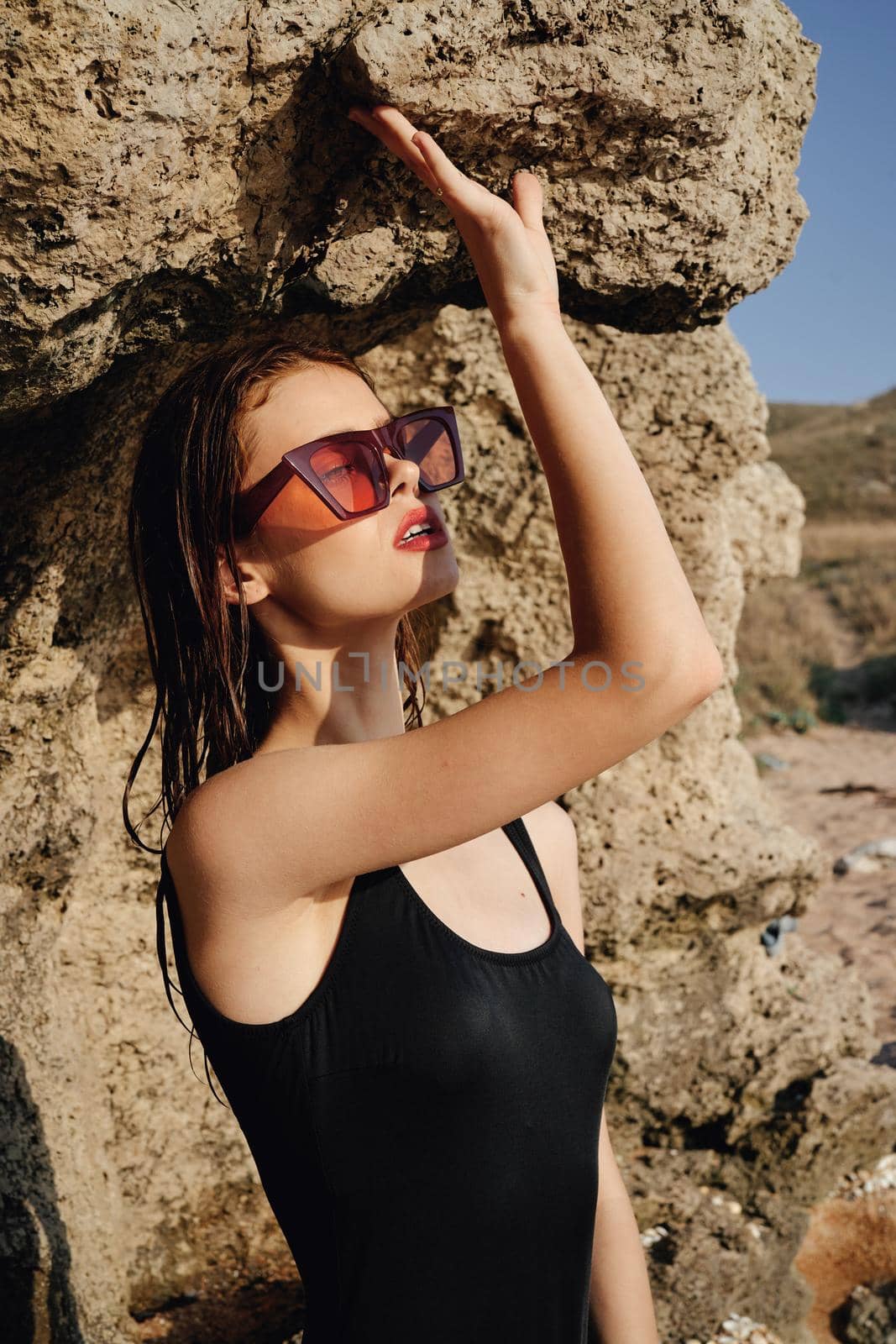 woman in black swimsuit sunglasses rocks posing summer luxury. High quality photo