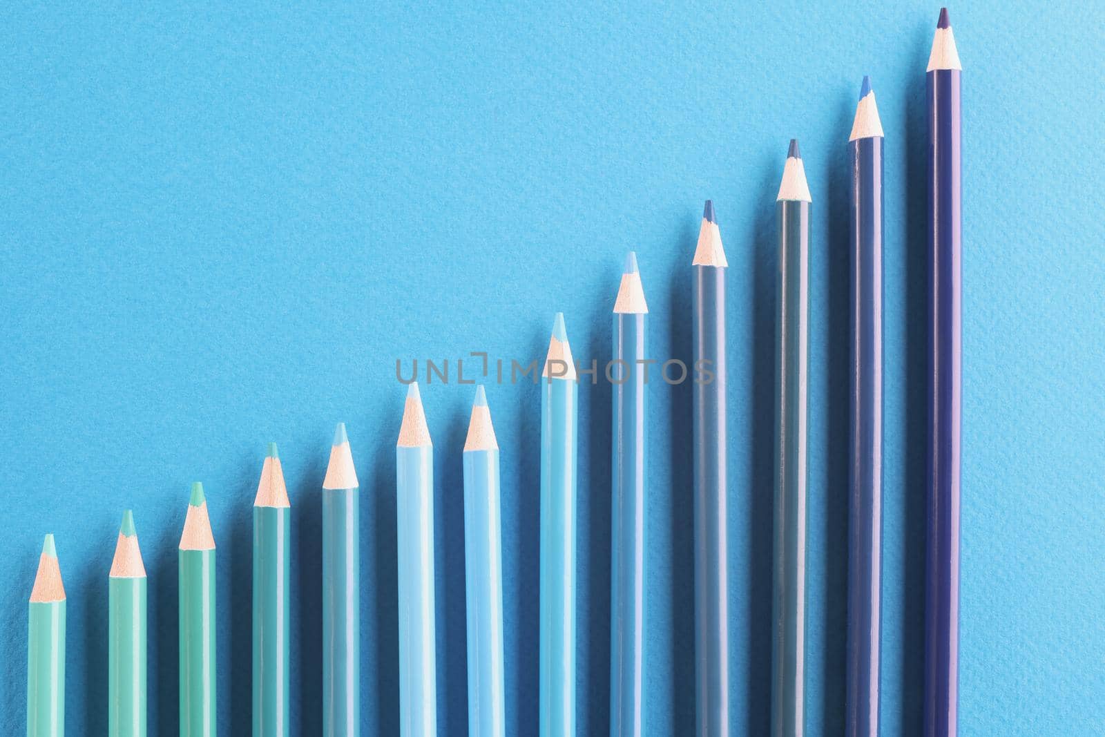Blue colored pencil set arranged in increasing way on surface and not exactly in row by kuprevich