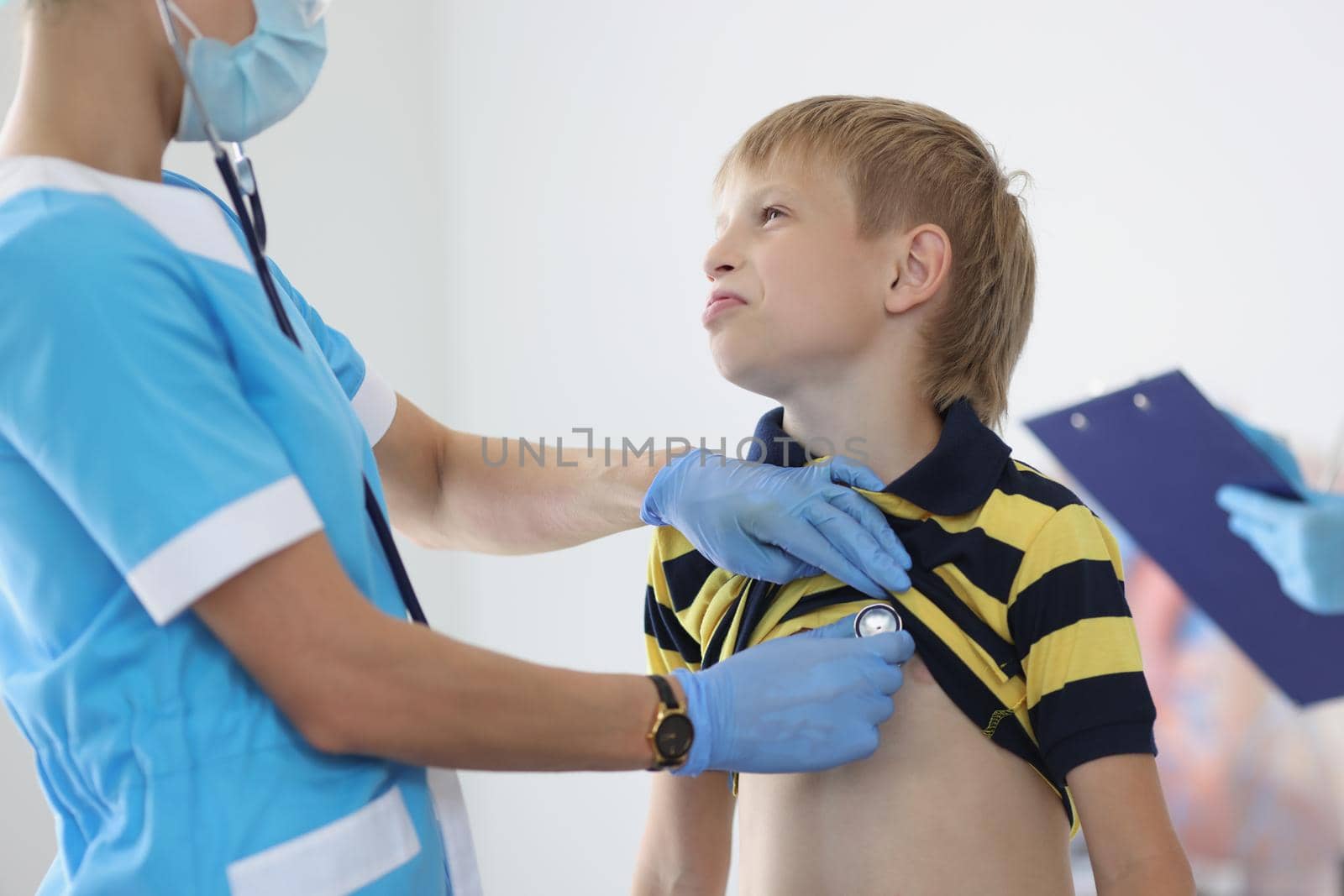 Female pediatrician listening to boy kid breathing with stethoscope tool, appointment at doctor by kuprevich