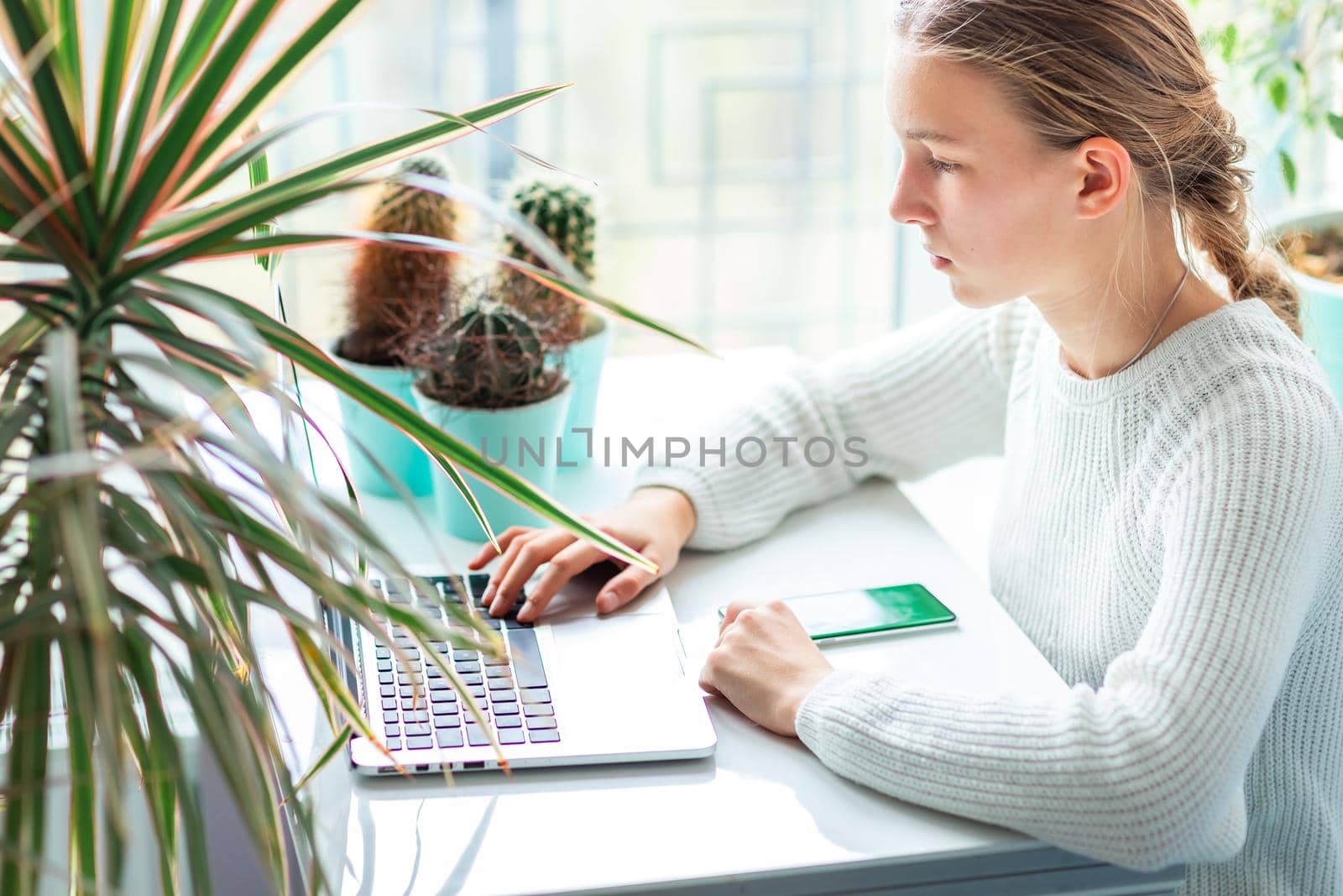 Beautiful teenage young school girl working at home in her room with a laptop studying in a virtual class. Distance education and learning concept during quarantine