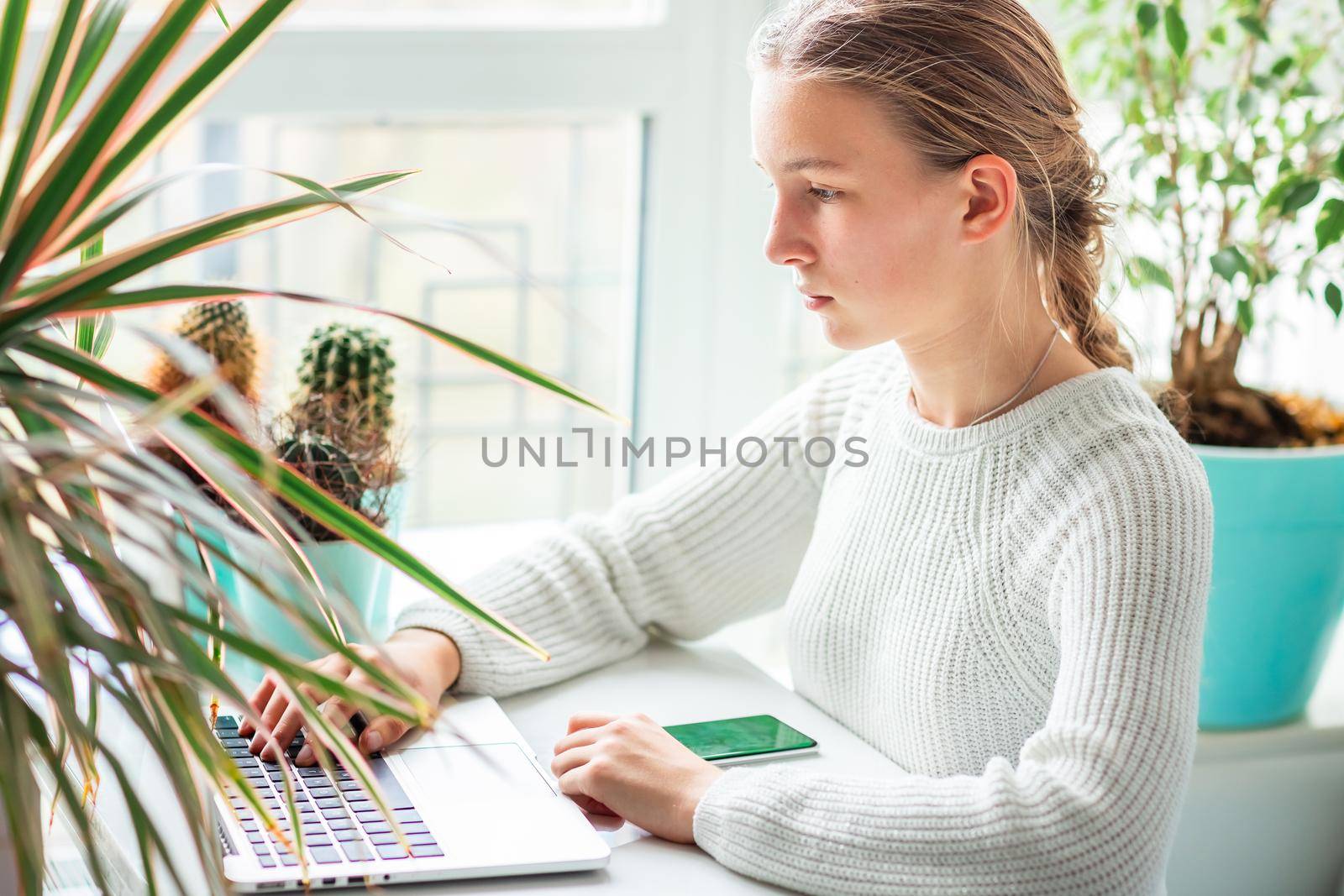 Beautiful teenage young school girl working at home in her room with a laptop studying in a virtual class. by Len44ik