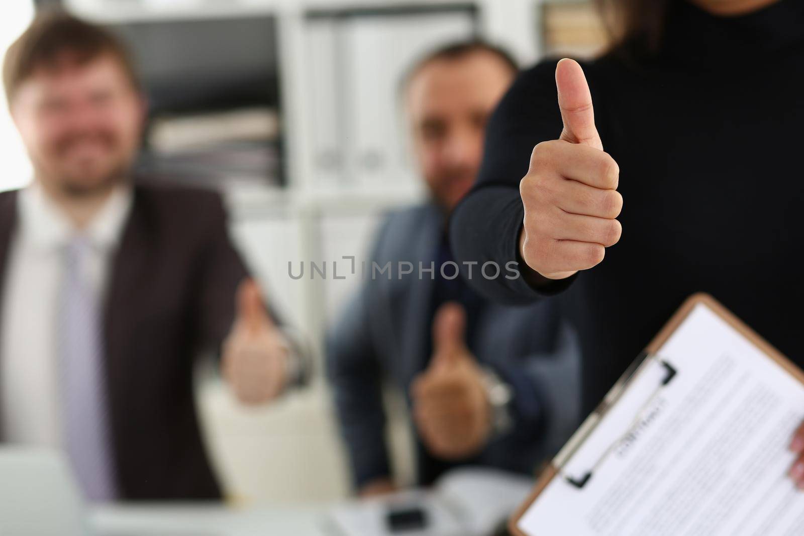 Close-up of group of young businesspeople happy to make good deal show thumbs up. Business partners made successful agreement in office. Business concept
