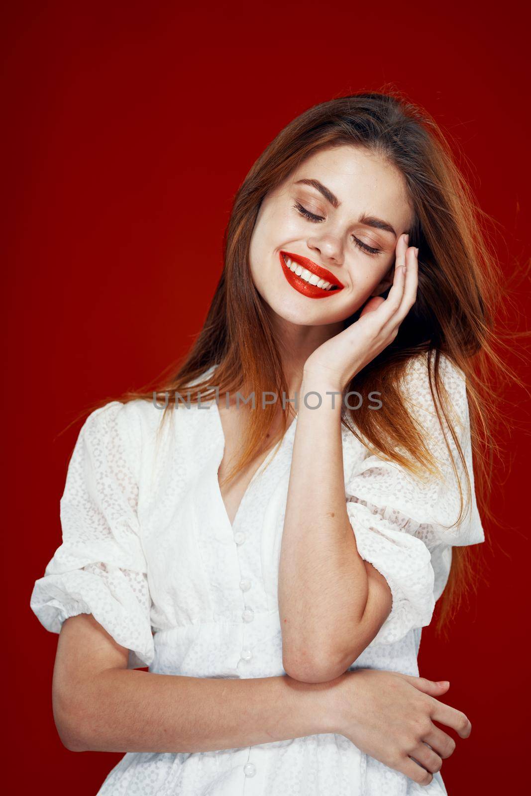 cheerful red-haired woman with red lips white dress red background. High quality photo