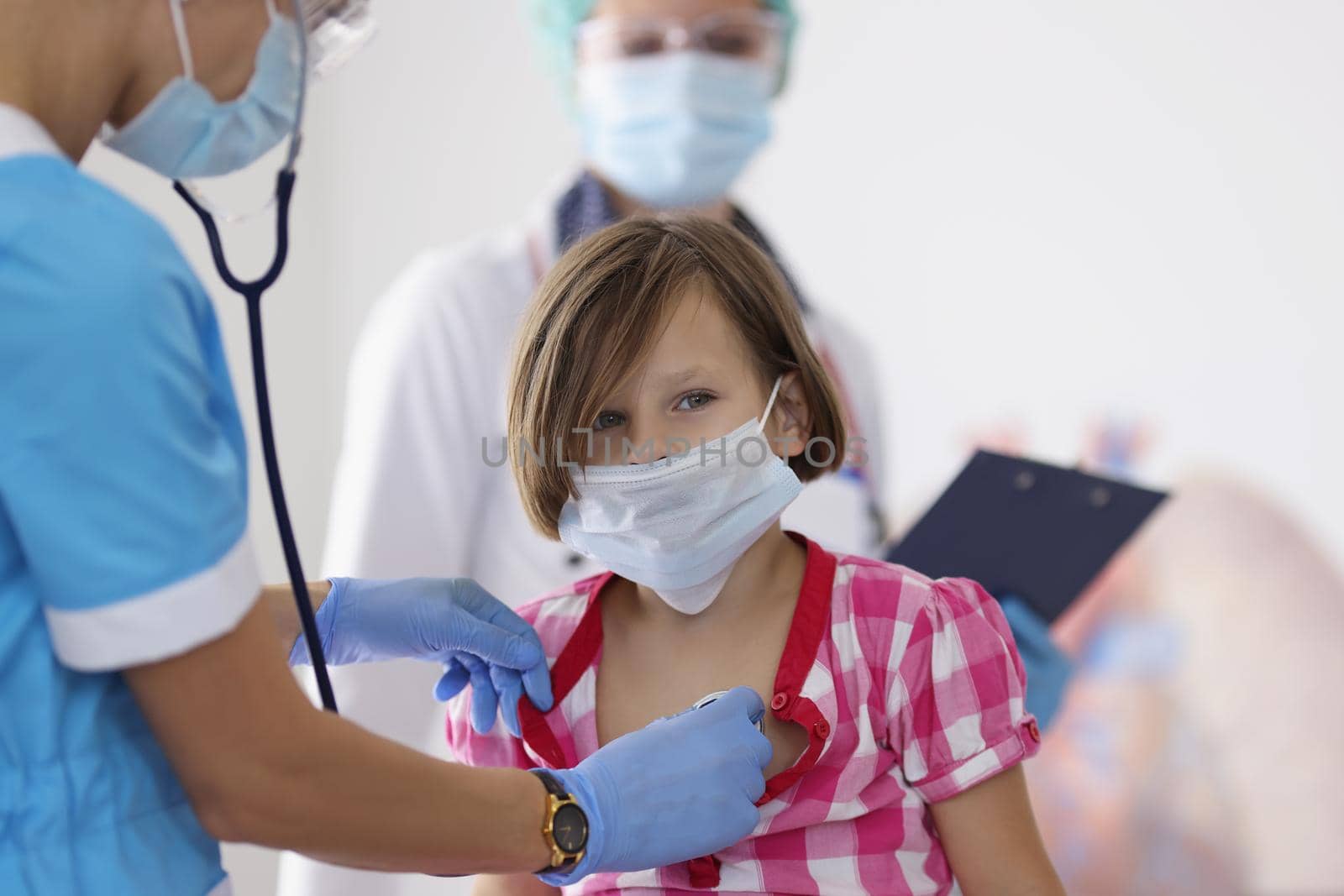 Girl being examined by pediatrician doctor with stethoscope tool by kuprevich