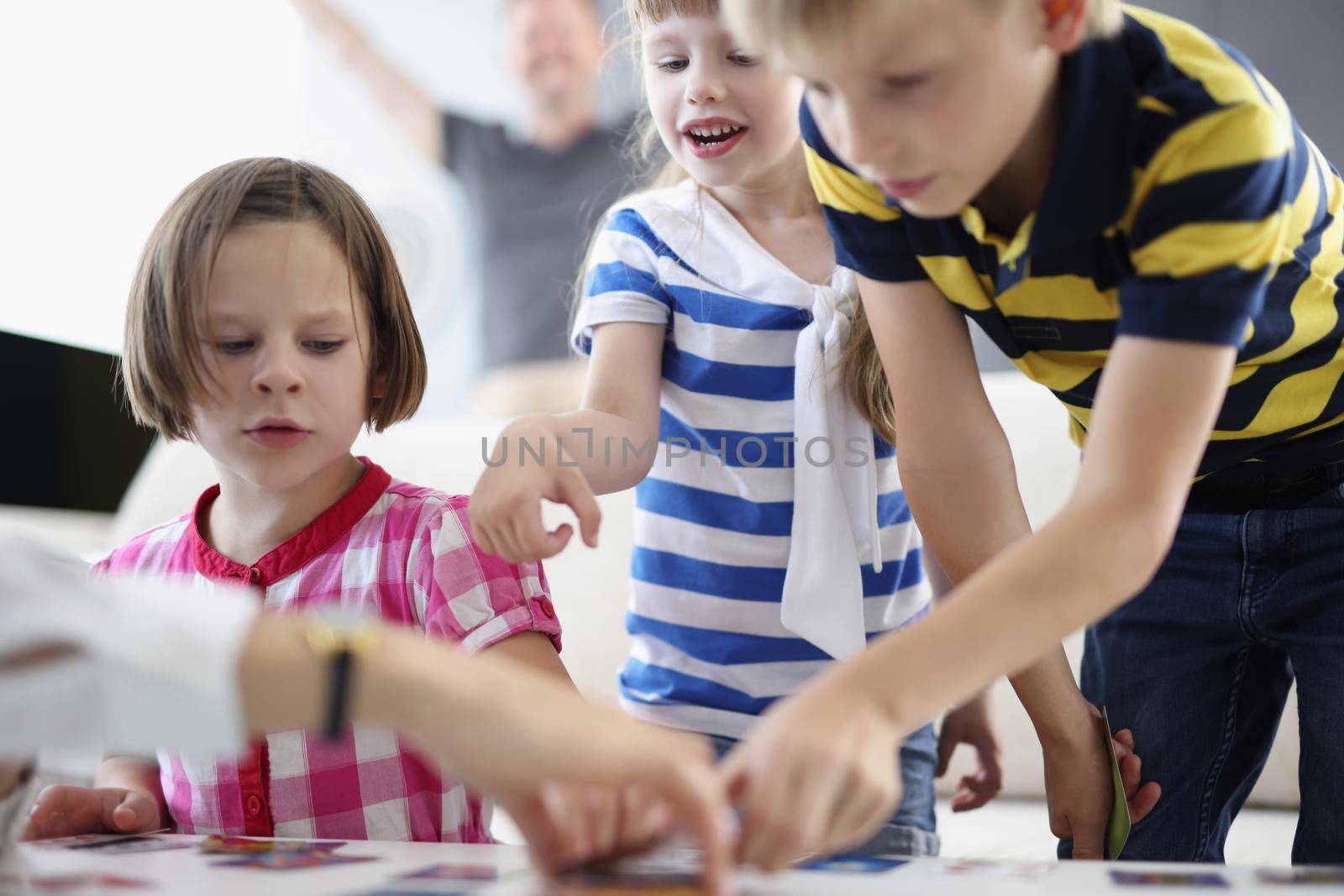 Kids friends busy with playing card game on table at home by kuprevich