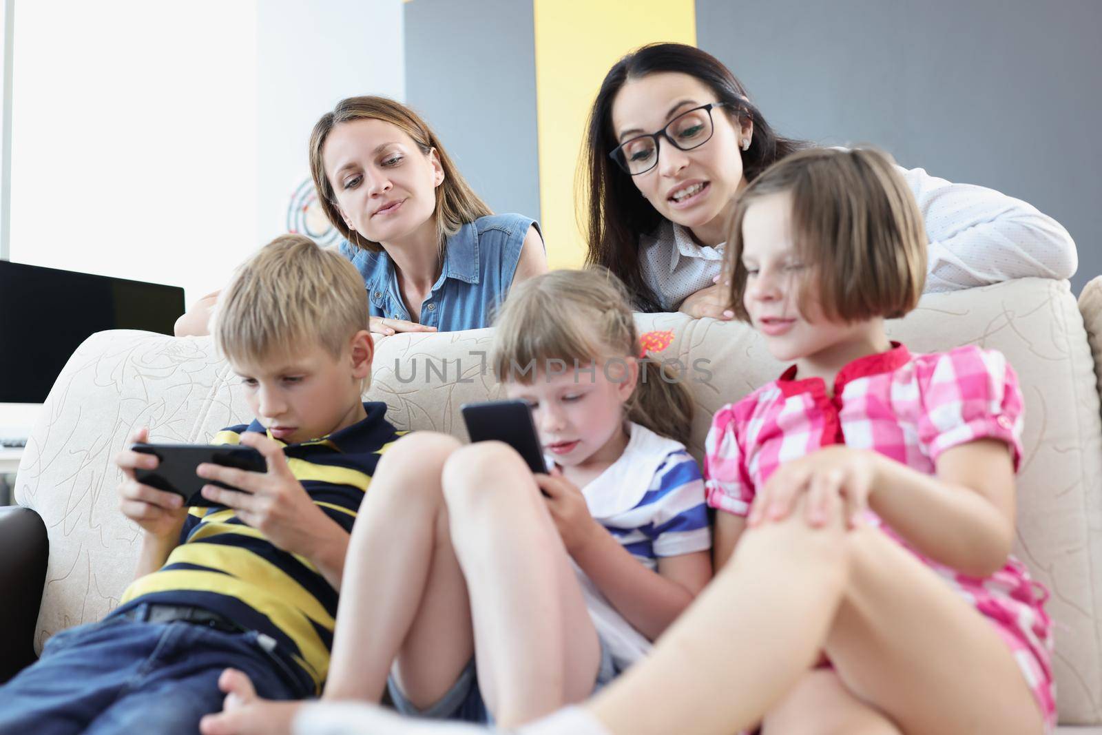 Kids play online games on mobile phones and mums control watching them by kuprevich