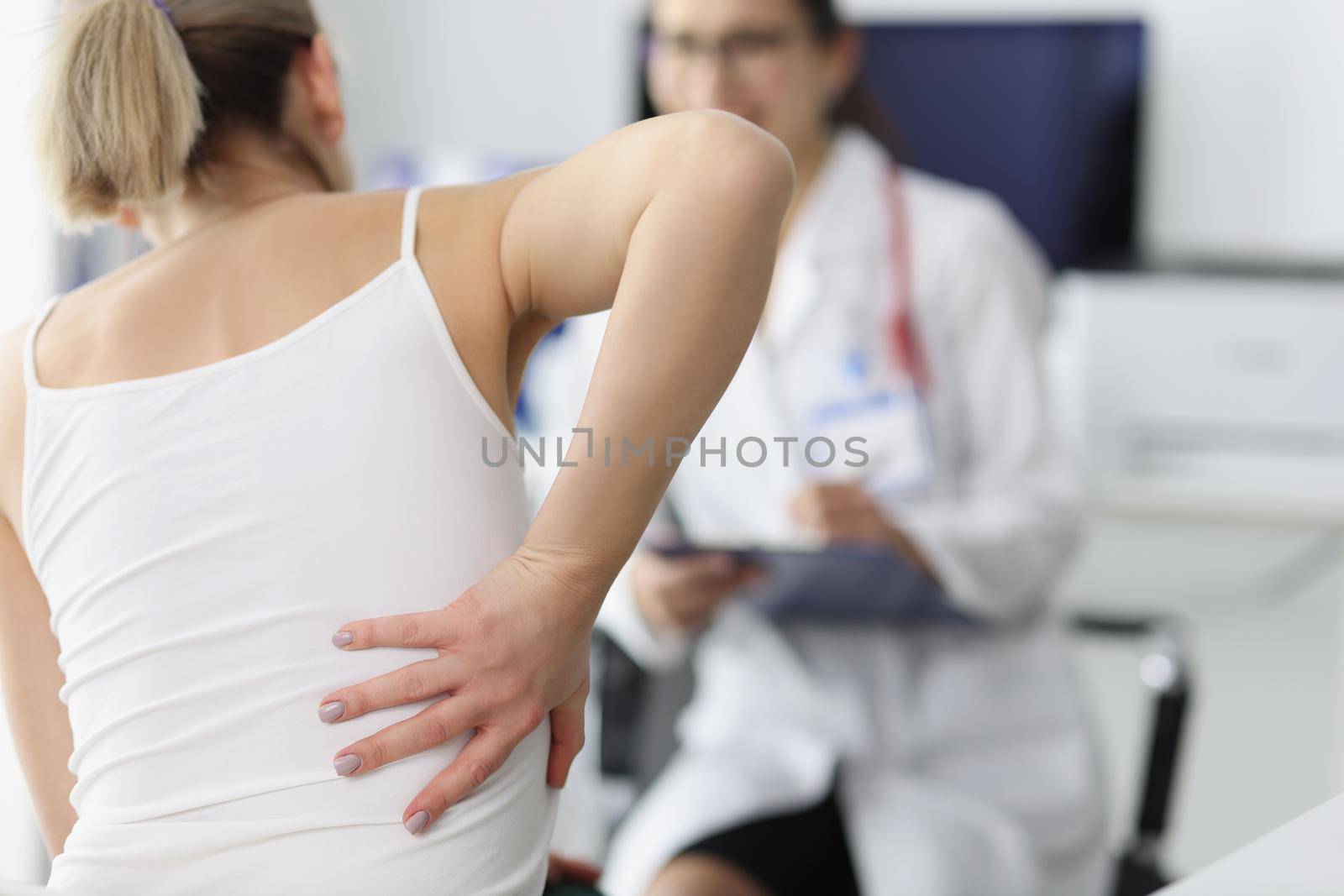 Close-up of female patient complain on back pain and touch side of body. Doctor listen to client and propose diagnostic. Healthcare, trauma surgeon concept