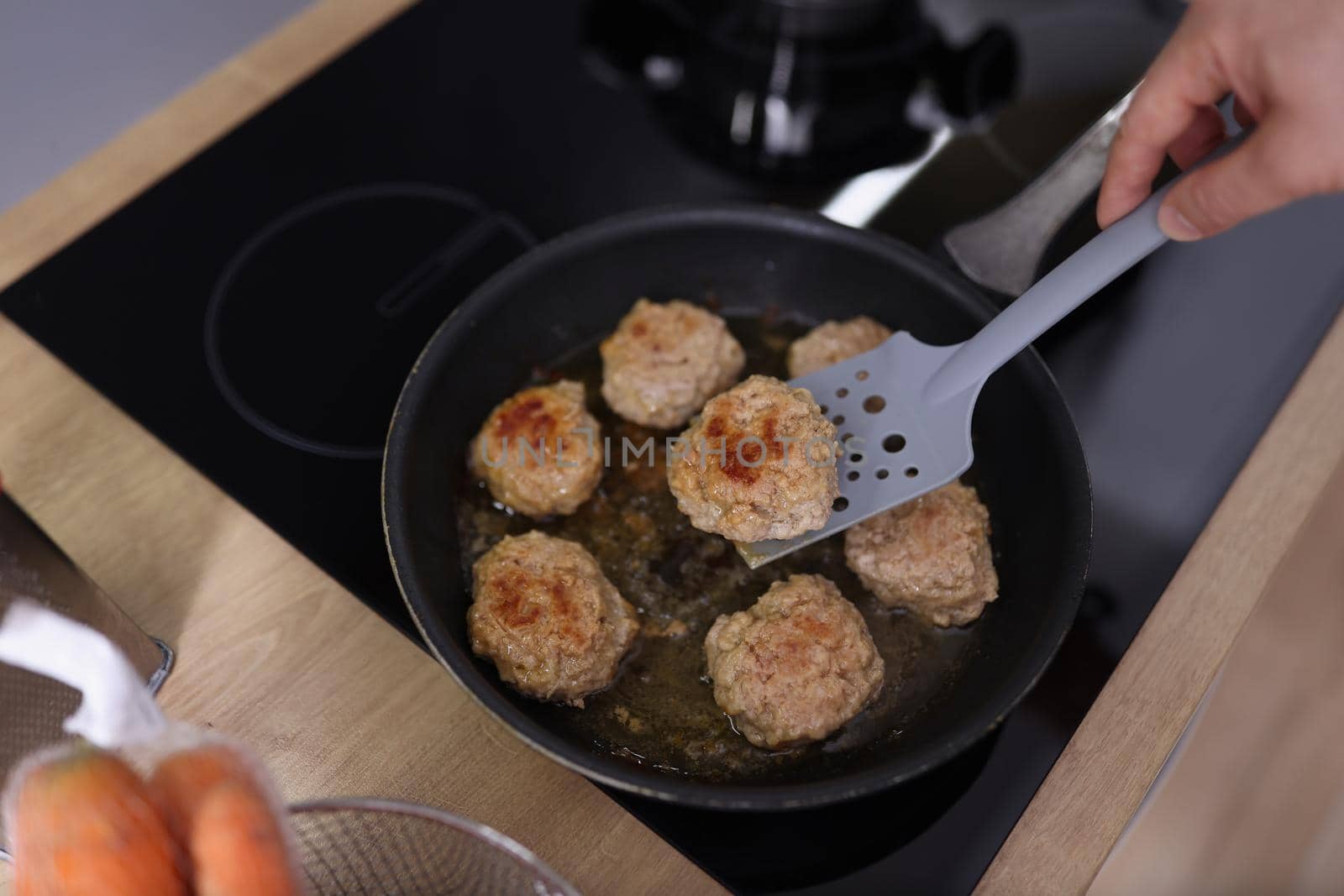 Top view of meat balls beginning to fry in oil in frying pan on kitchen stove. Housewife cooking fresh meal using tool. Chef, food, eating, dish concept