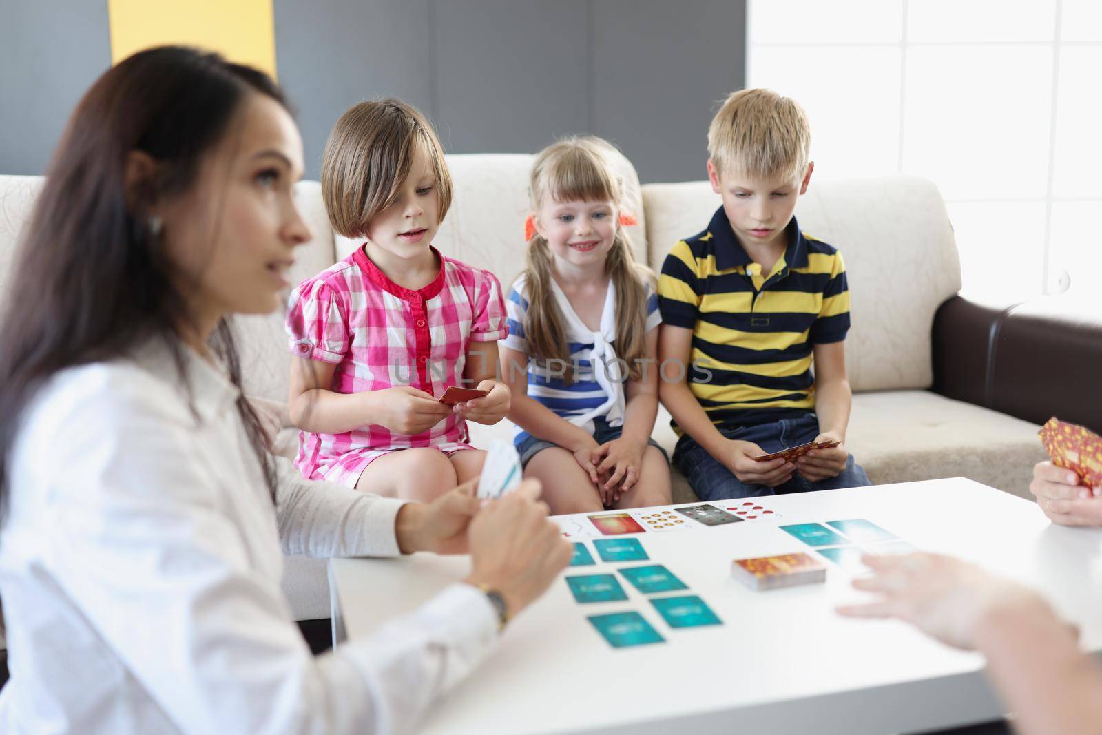 Portrait of group of kids spending time in kindergarten with female teacher. Woman entertain children with games and active pastime. Childhood, fun concept