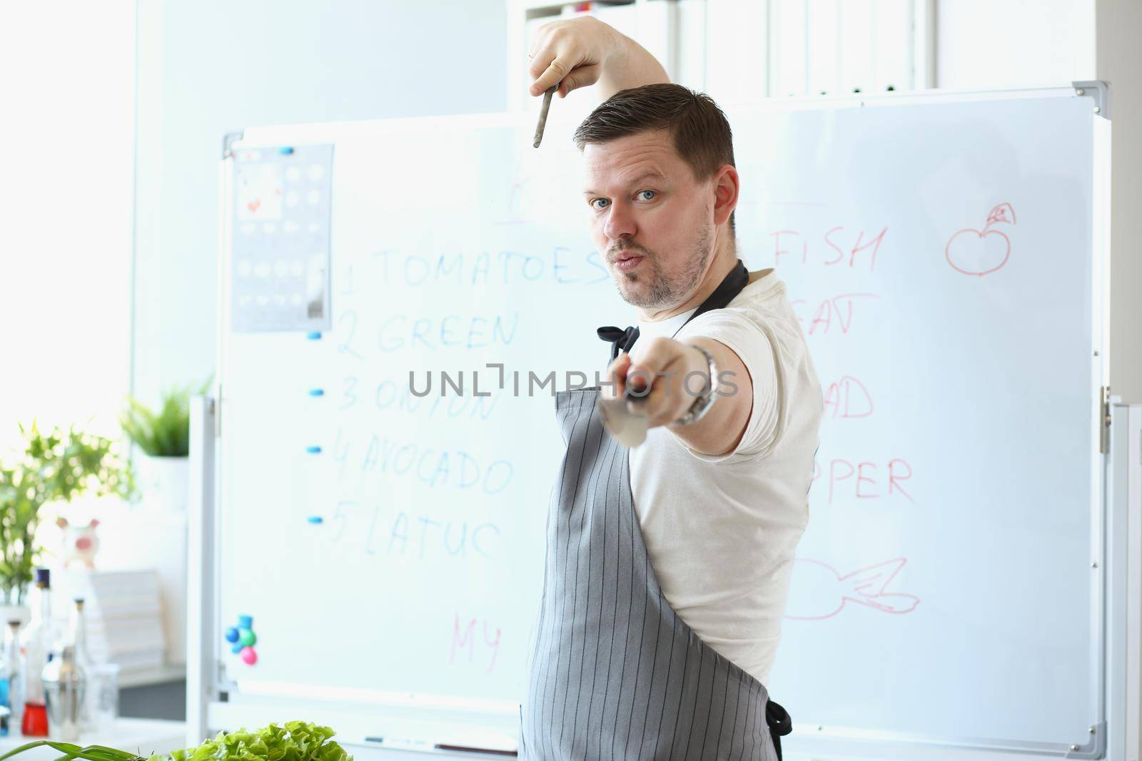 Portrait of attractive male chef standing in apron and pretend hes fighter with cooking knife. Blogger chef discover healthy eating habits. Food concept