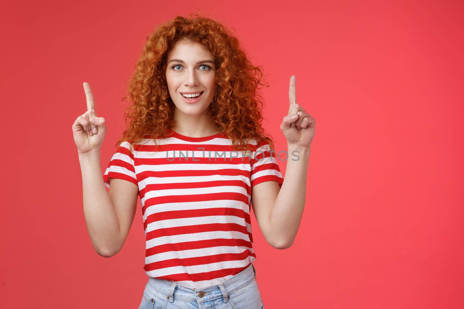 Excited good-looking cheeky redhead ginger girl curly natural hair pointing raised index fingers up smiling impressed thrilled advising store directing promo advertising awesome haircare product.