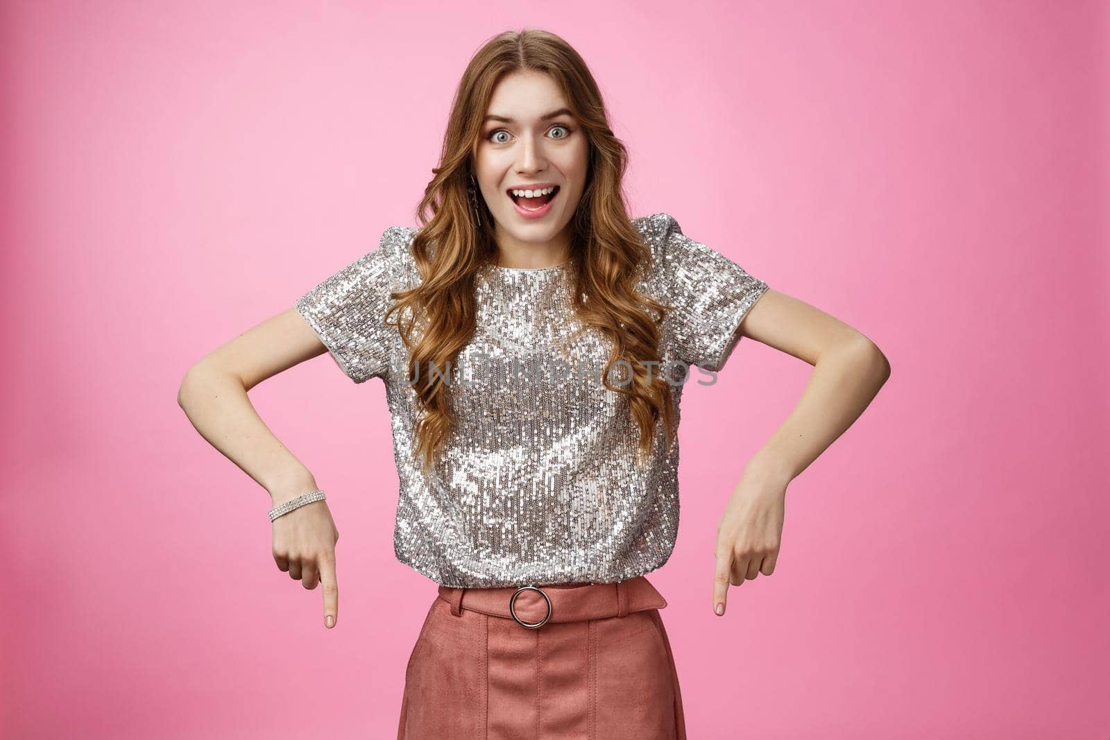 Studio shot impressed excited attractive young fashionable woman drop jaw thrilled pointing down index fingers amazing awesome promo advertisement, showing copy space astonished overwhelmed.