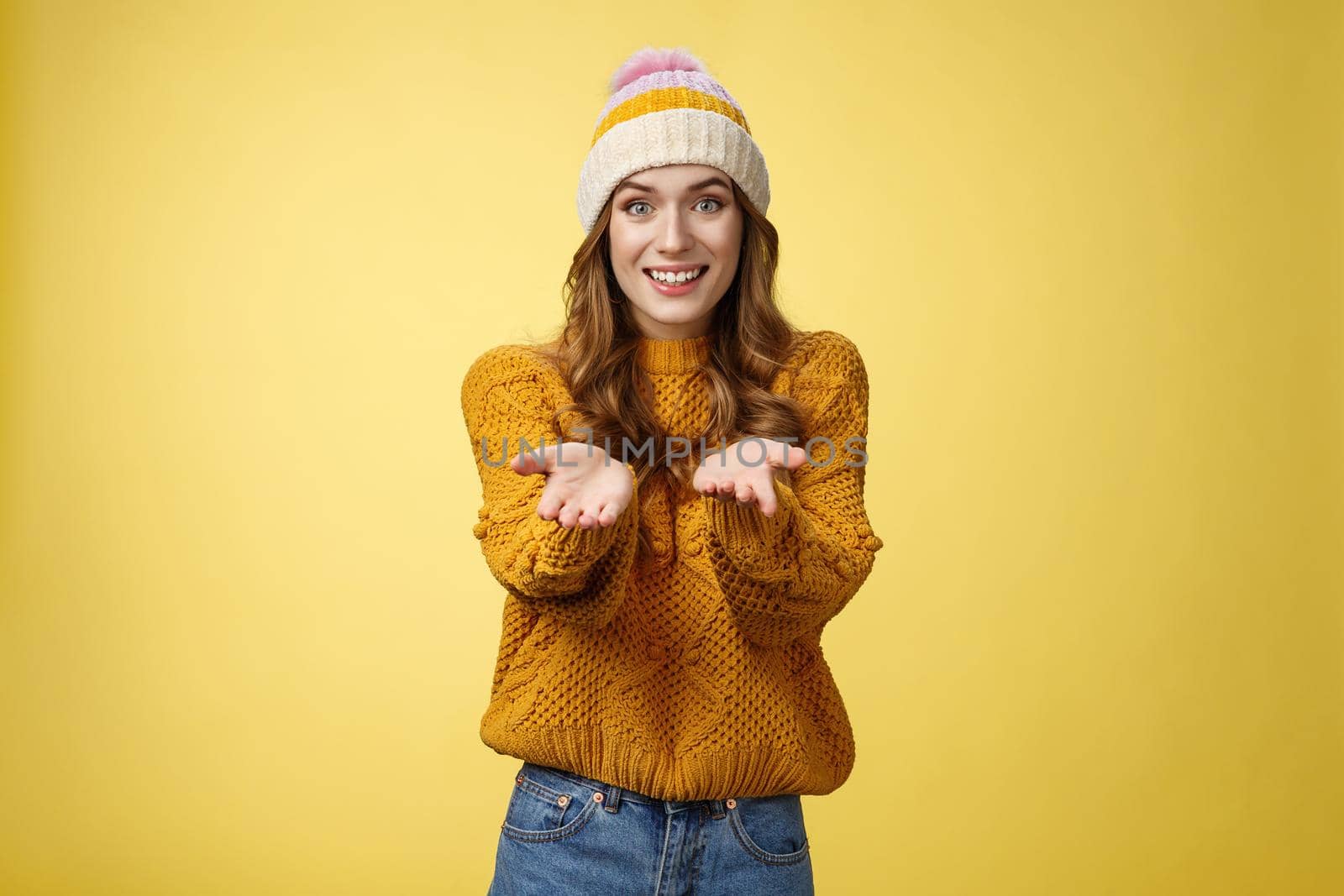 Girl suggesting take her heart smiling broadly friendly extending arms towards camera proposing help smiling delighted feeling upbeat wanna thank friend grateful appreciating effort, yellow wall.