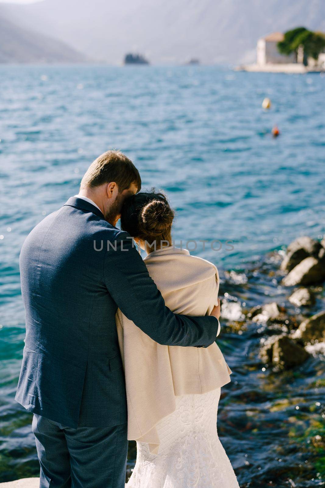 Bride and groom hug on the shore of the bay. Back view. High quality photo