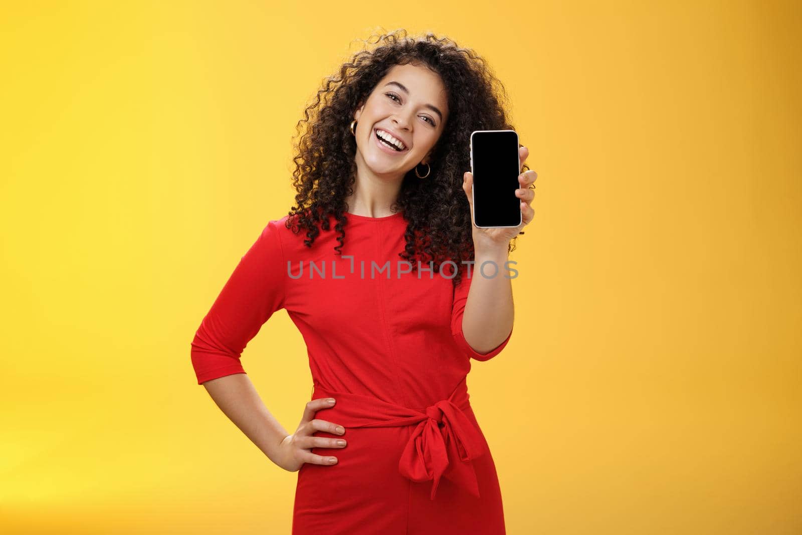 Carefree satisfied and happy attractive businesswoman presenting her best friend new mobile phone showing smartphone at camera laughing and smiling joyfully delighted with new purchase by Benzoix