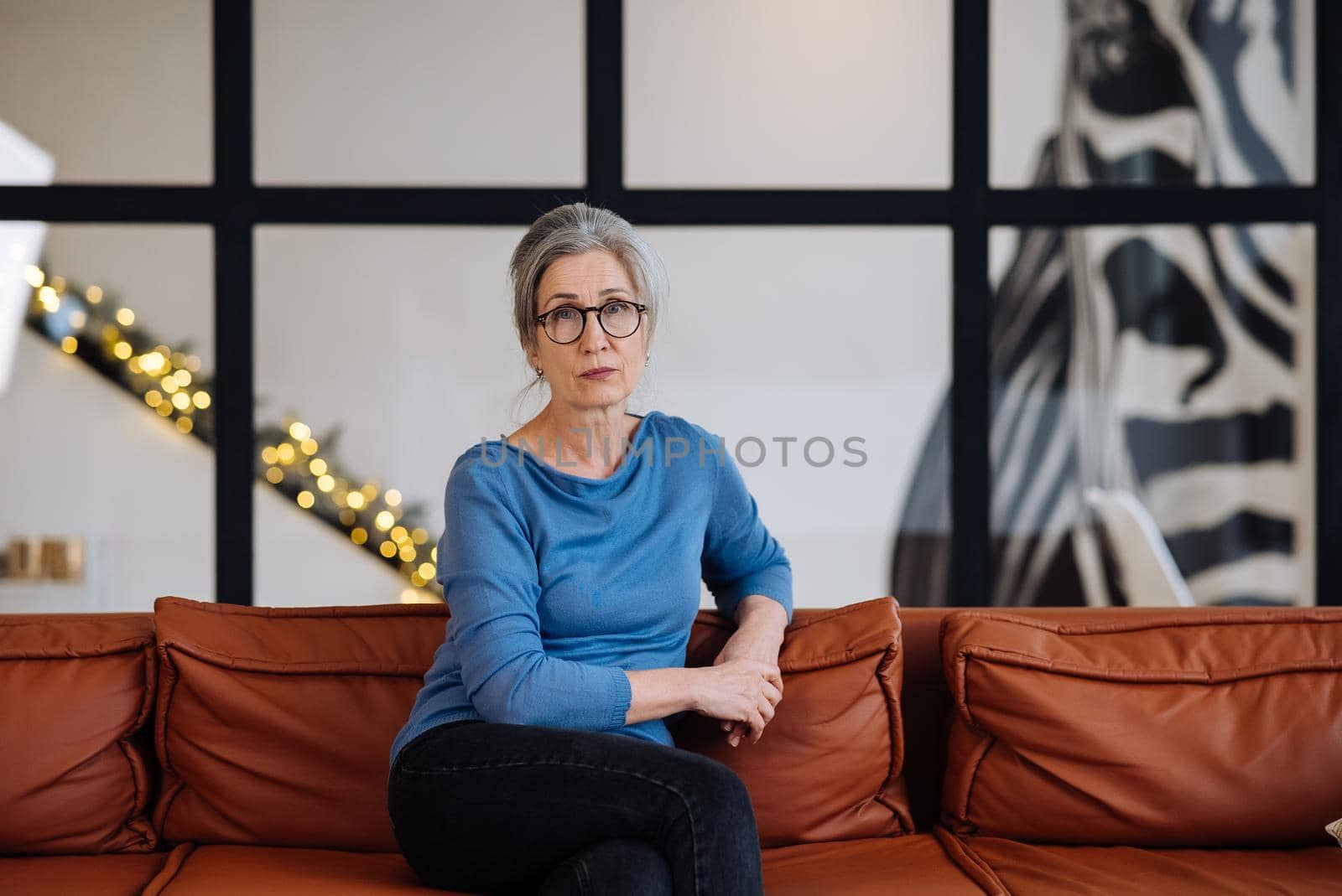 Portrait of a Cheerful Middle Aged Woman Sitting at the Sofa in the Living Room, Looking at Camera.