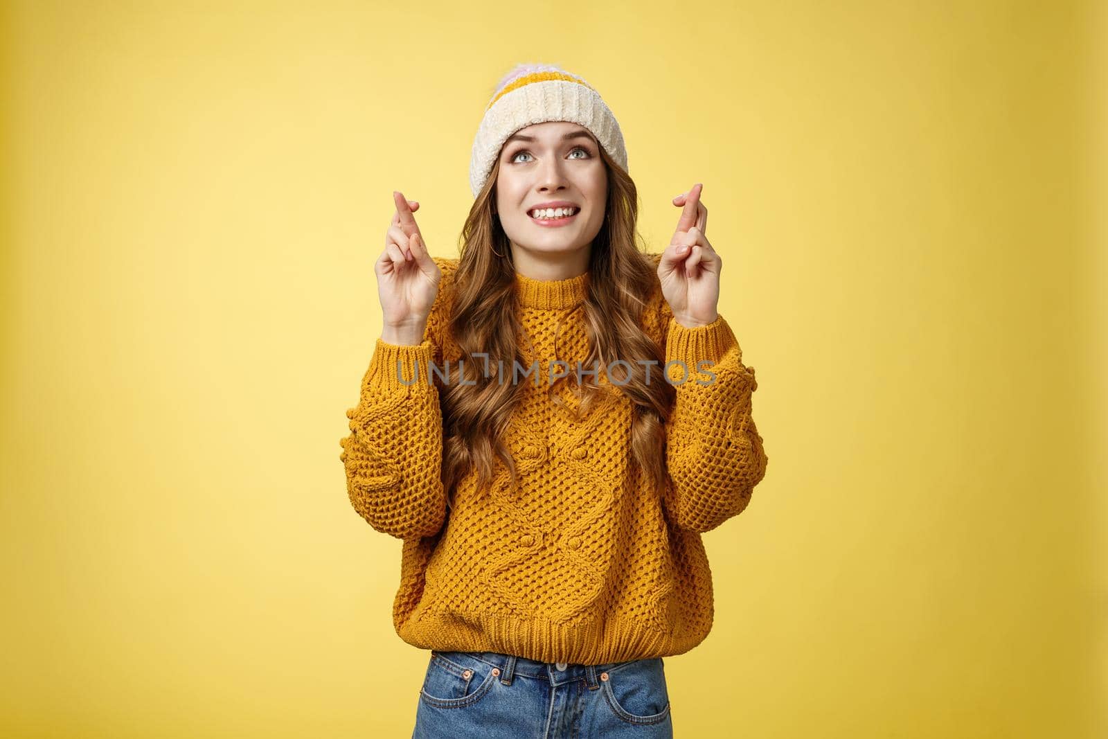 Nervous cute optimistic hopeful young attractive stylish woman praying god make wish look sky faithfully smiling cross fingers good luck wanna fulfill dream, standing anticipating yellow background.