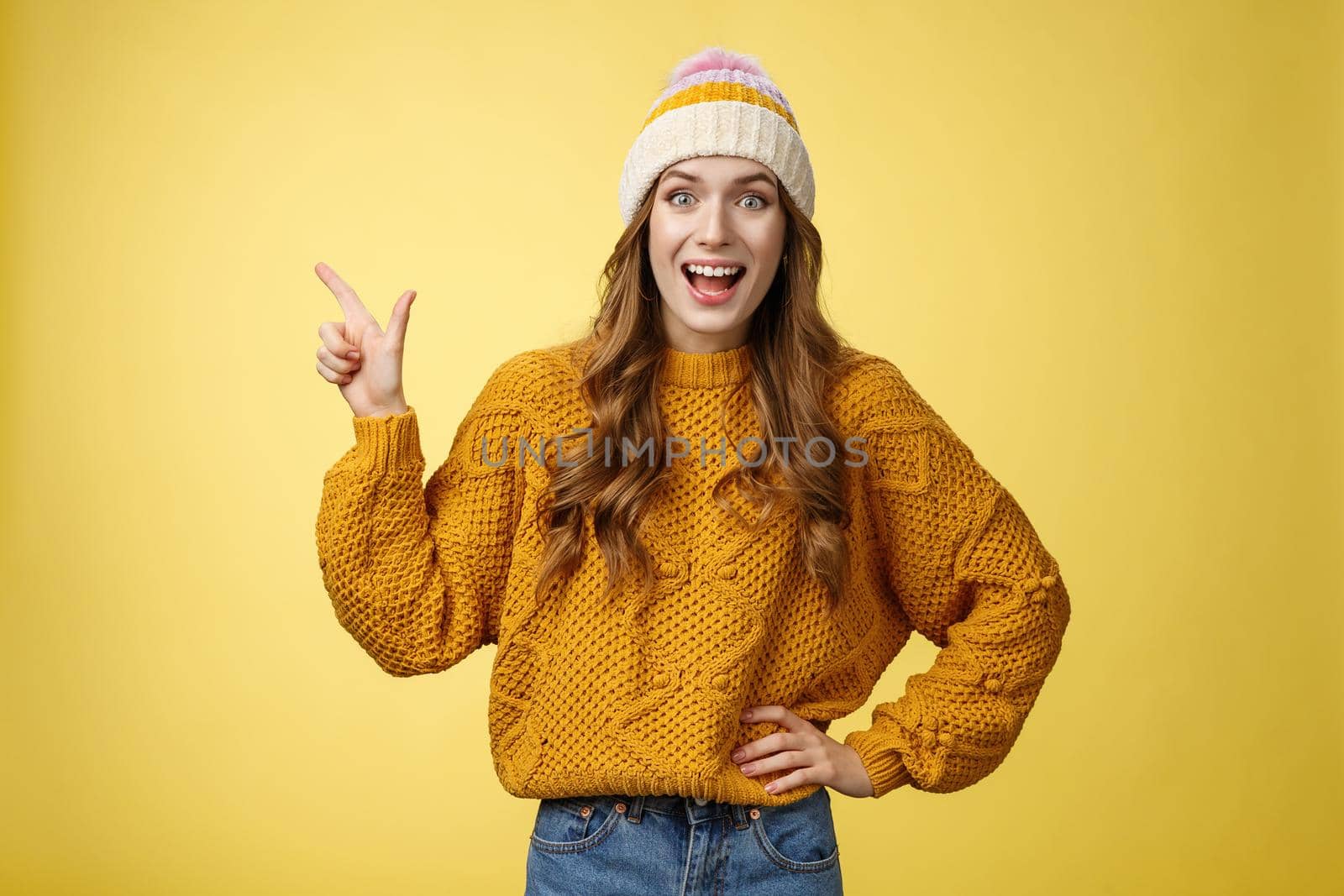 Amazed surprised carefree happy young joyful woman laughing surprised widen eyes wondered see funny prank pointing upper left corner excited discussing friends new shopping centre, yellow background.
