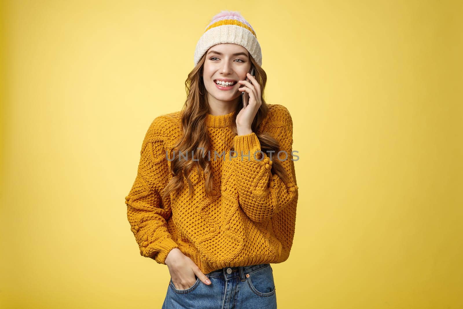 Carefree sociable good-looking outgoing woman calling friend talking happily smartphone have pleasant funny conversation smiling giggling look away hold hand pocket, standing yellow background by Benzoix