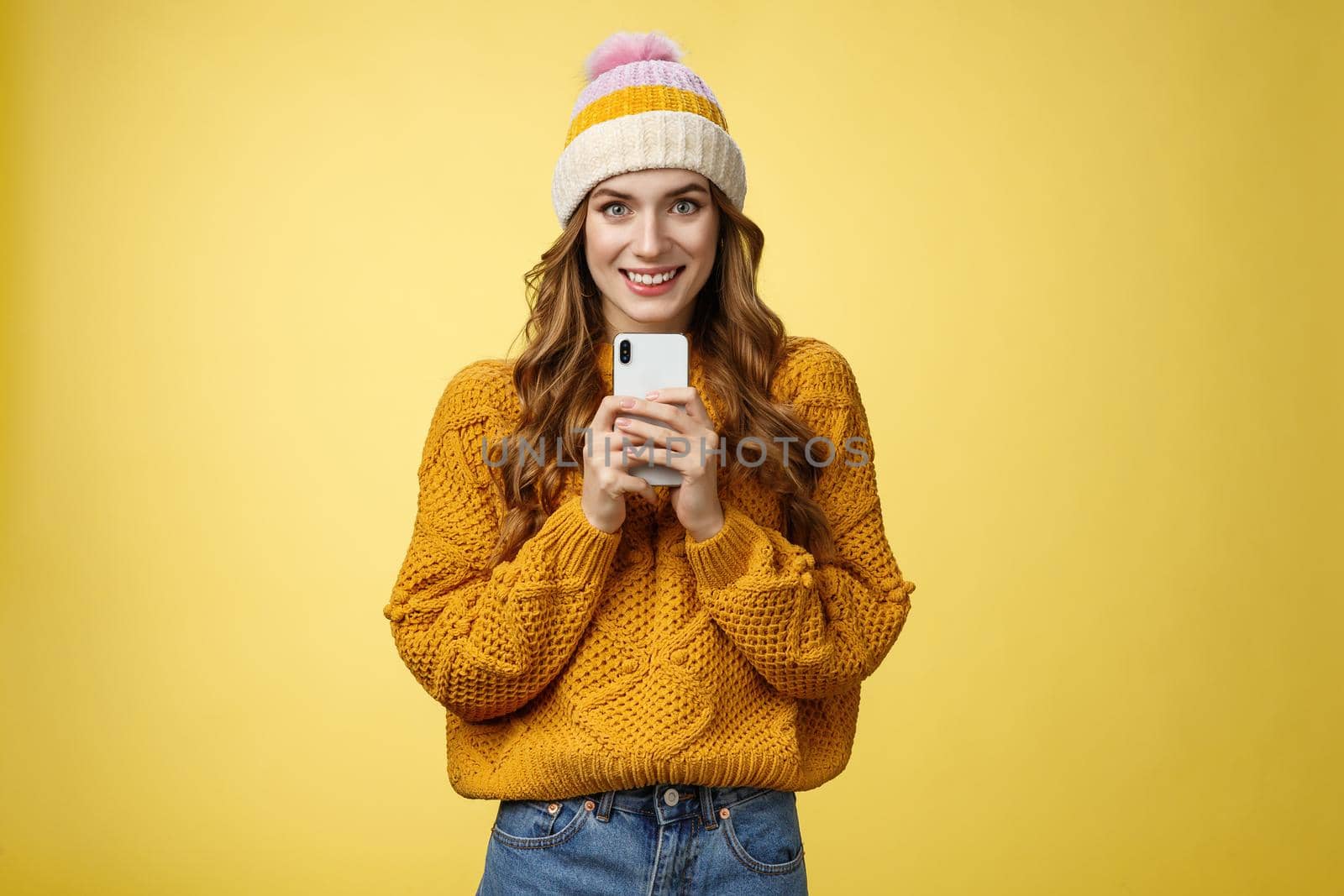 Smiling friendly-looking charming young trendy girlfriend holding brand new smartphone satisfied smiling upbeat receiving mobile phone birthday present grinning satisfied, taking photo you by Benzoix