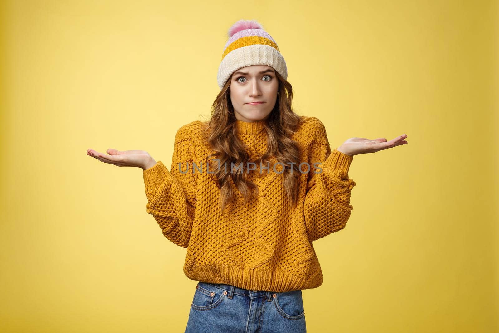 How should I know. Portrait confused perplexed worried cute female assistant shrugging spread hands sideways clueless unaware cannot understand what happened unsure, unaware yellow background.