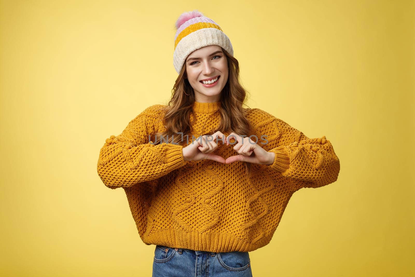 Girl brings peace love show heart gesture tilting head friendly smiling expressing sympathy passion confessing boyfriend warm feelings, heartbit sign, grinning flirty, standing yellow background.