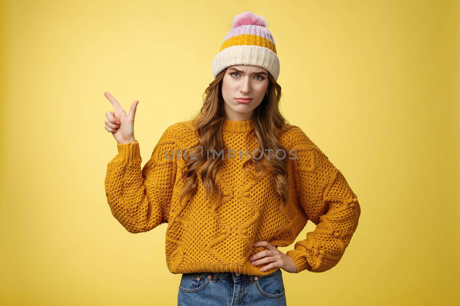 Meh lame promo. Portrait picky arrogant unimpressed complaining female fashionable customer pointing upper left corner frowning cringing displeased unsatisfied, dislike bad offer, yellow background.