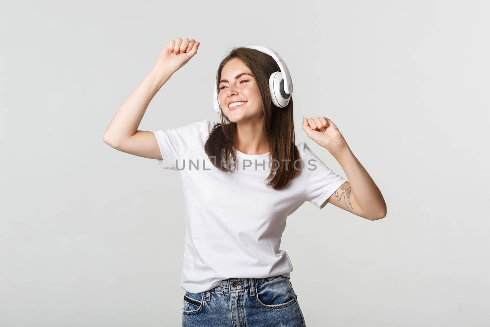 Carefree attractive girl dancing and listening music in wireless headphones.
