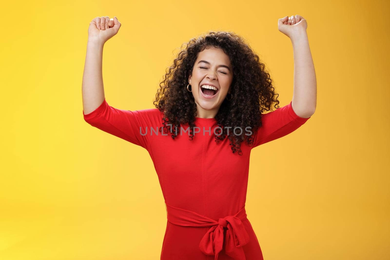 Oh yeah I am winner, on top of world. Excited ambitious and happy young successful busiensswoman getting promotion yelling yes with broad smile and closed eyes lifting hands in triumph and celebration by Benzoix