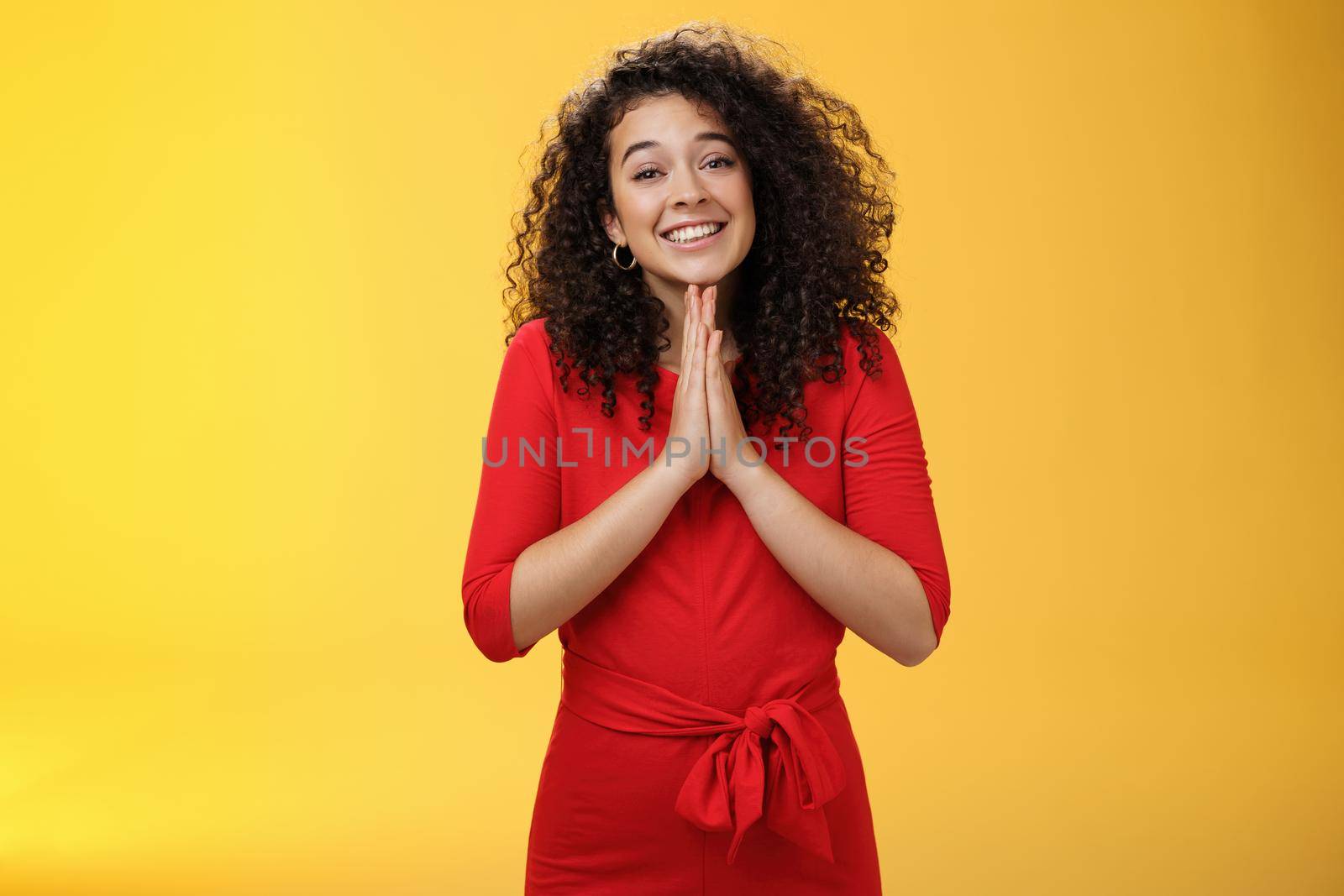 Girl with angel smile making eyes as wanting friend make favour, holding hands in pray, grinning and gazing with anticipation as begging for help standing silly and cute against yellow background.