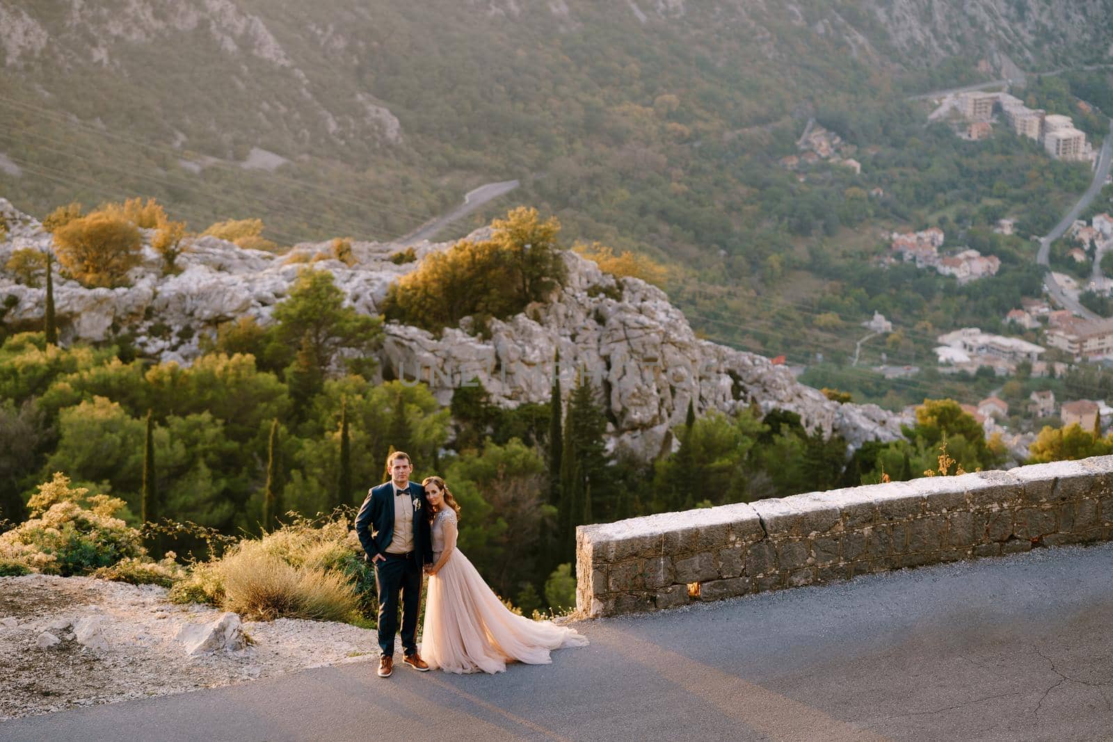 Groom and bride stand embracing on the road in the mountains. High quality photo