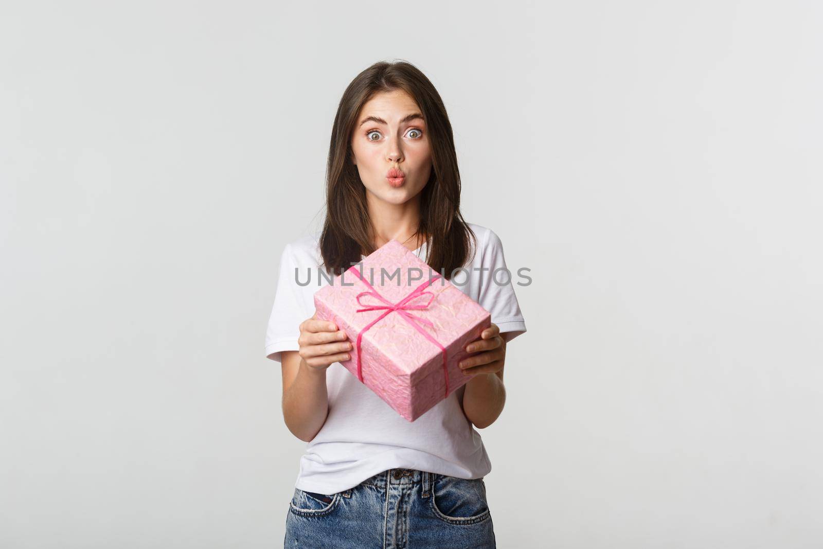 Surprised happy birthday girl receiving wrapped gift, white background.
