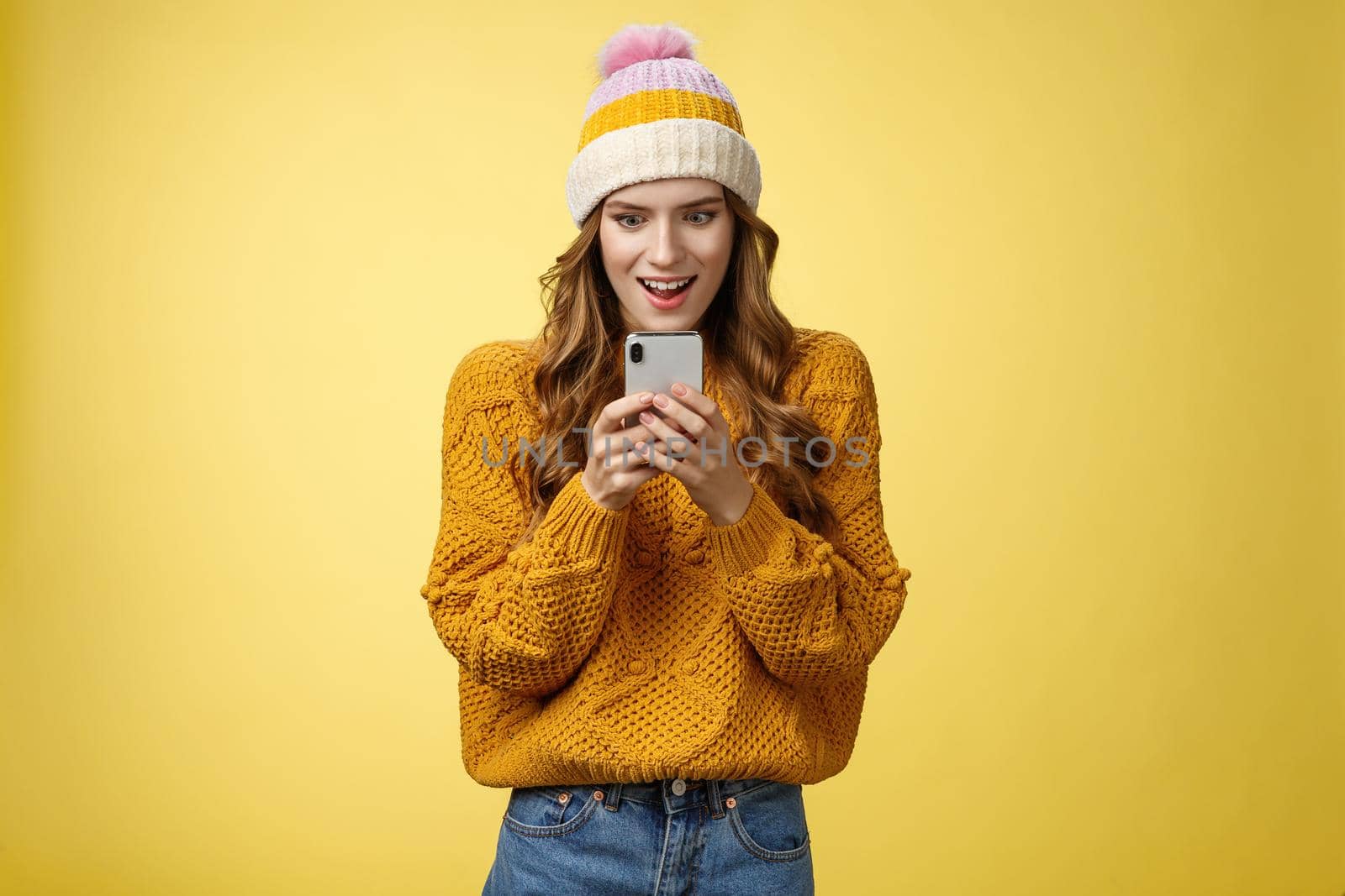 Amazed attractive stylish woman receive message smartphone awesome promotion ready shopping online smiling thrilled excited look mobile phone display, posing yellow background by Benzoix