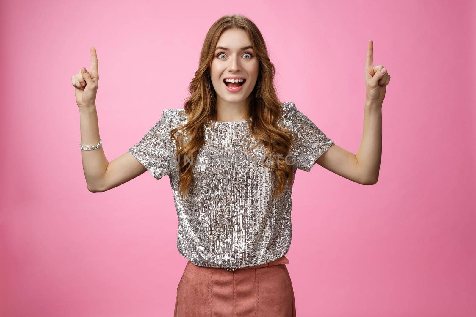 Impressed speechless attractive fashionable girl excited saw incredible sale promotion pointing raised index fingers up top widen eyes thrilled wanna shopping, standing amazed pink background.