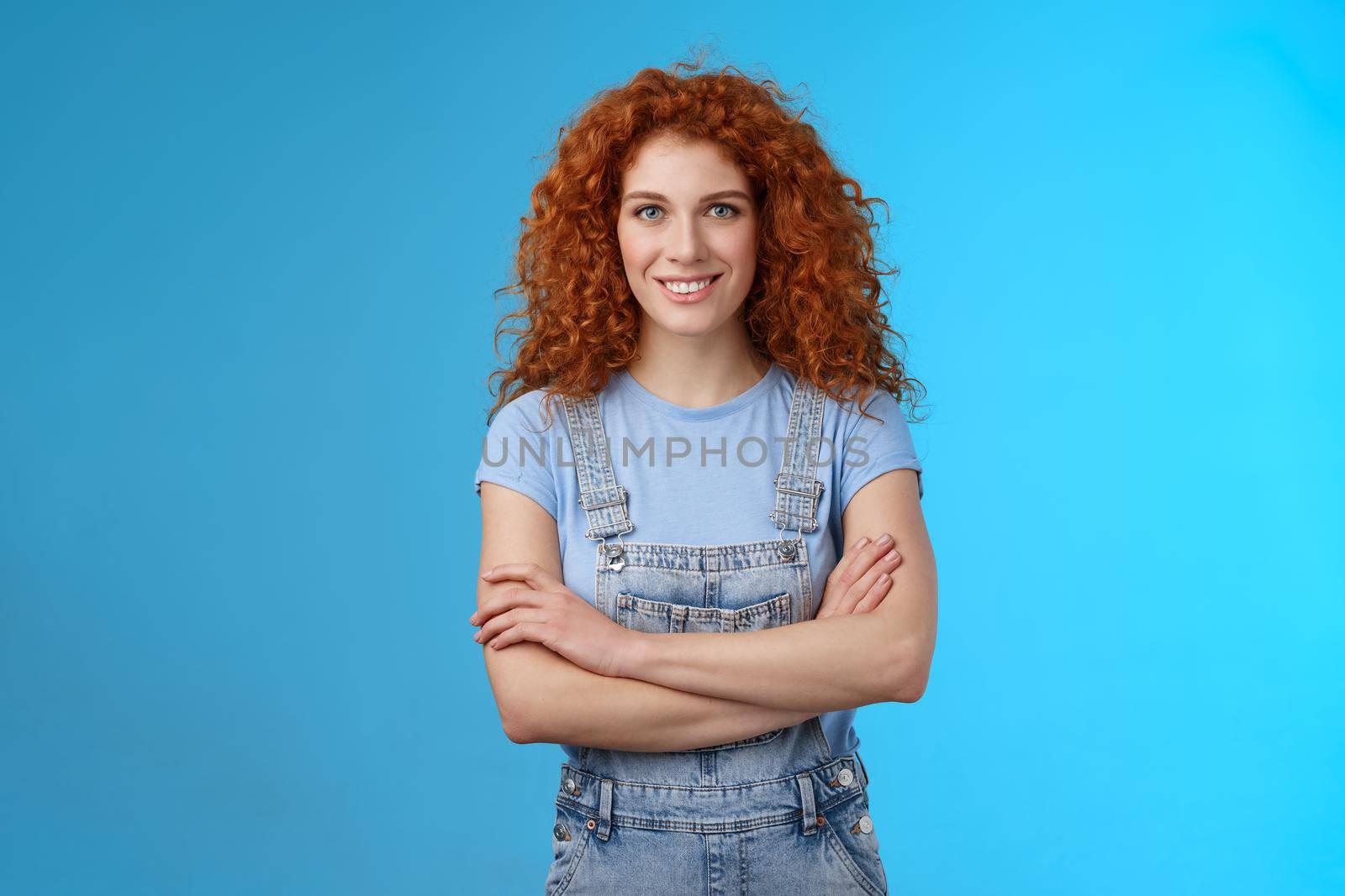 Motivated empowered sassy redhead female believe girl power cross arms chest self-assured confidently know how deal any problem smiling cheeky determined stand denim overalls blue background by Benzoix