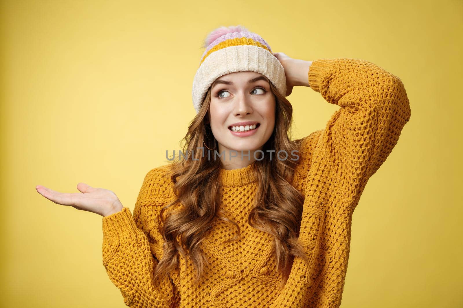 Oopsie sorry. Silly carefree charming flirty woman apologizing making foolish mistake grinning awkward scratch head shrugging hand put sideways, trying not look eyes, standing yellow background.