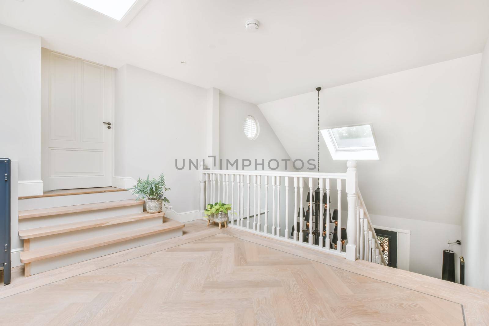 Top landing of stairs with wood floor and white walls
