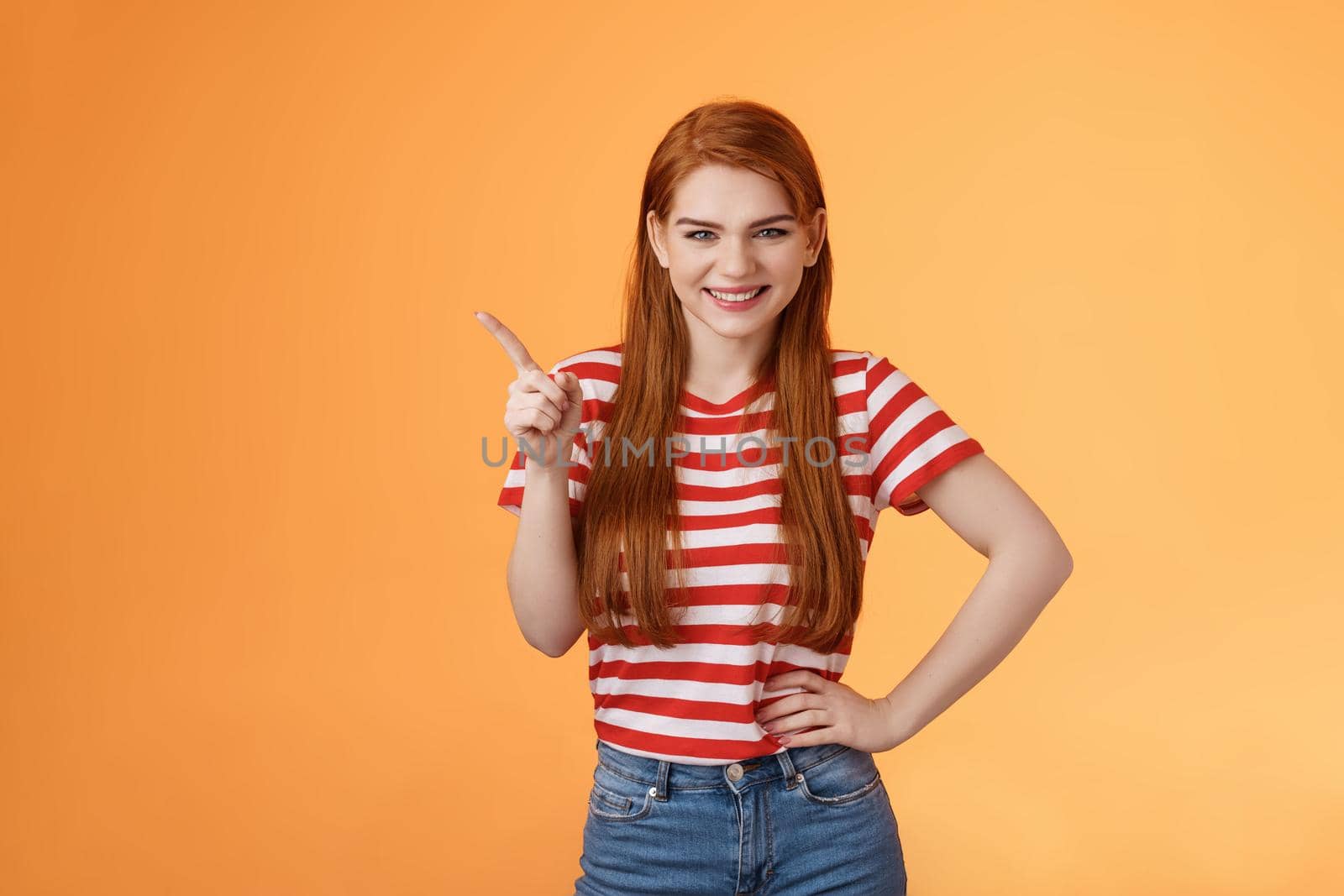 Cheerful sly redhead girlfriend have something interesting on mind, squinting cunning joyful smile, hold hand waist confident pose, pointing upper left corner give recommendation, orange background by Benzoix