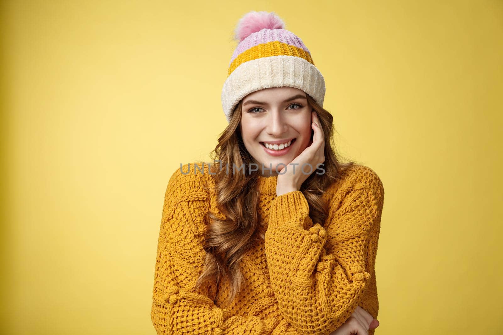 Dreamy tender romantic good-looking woman wearing warm hat knitted sweater giggling smiling flirty seducing you look interested happy, lean head palm listening curious story, yellow background.