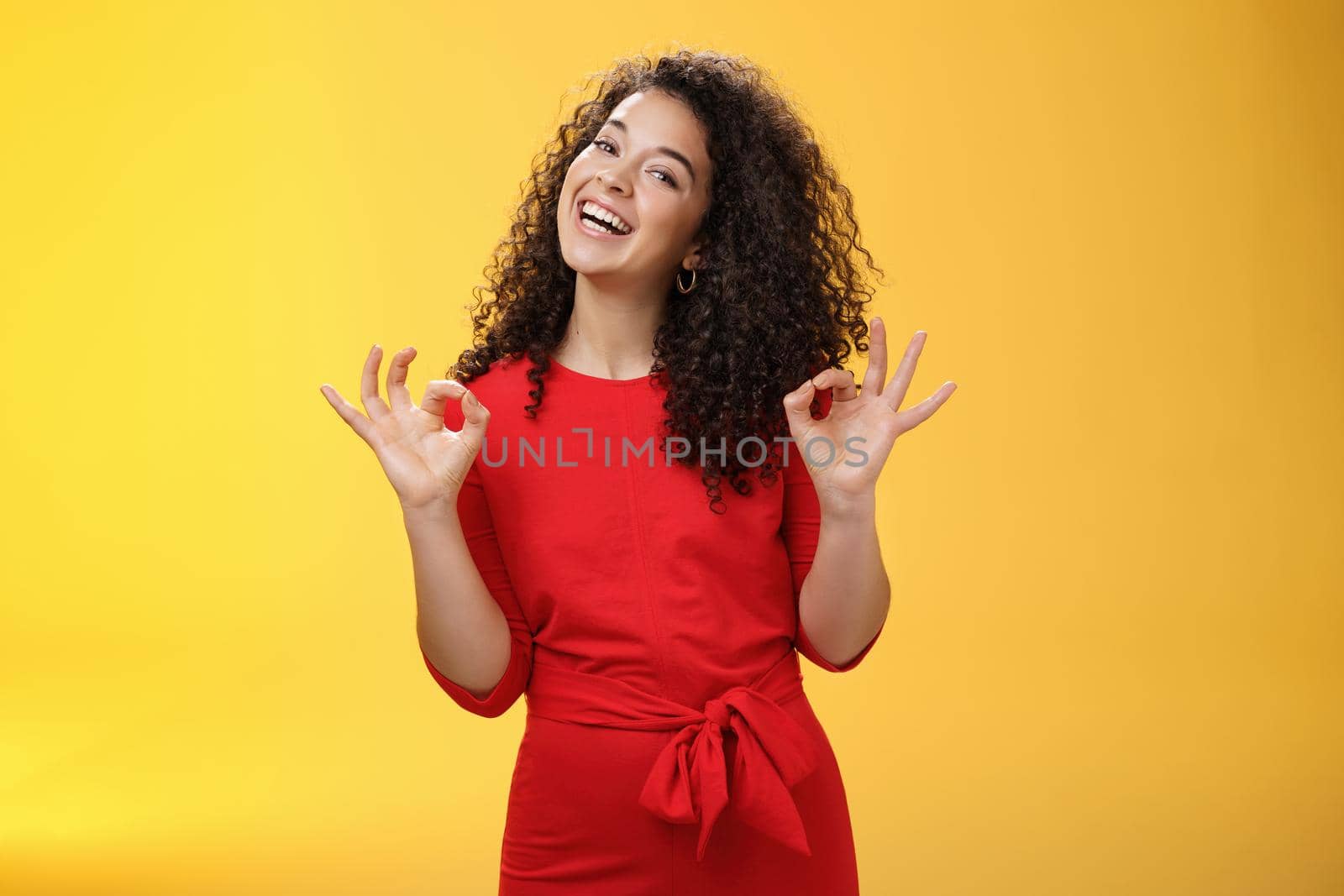 Charming girl living dream standing happy and satisfied as liking new apartment rent with boyfriend showing okay gesture and tilting head with broad smile approving cool place over yellow background.