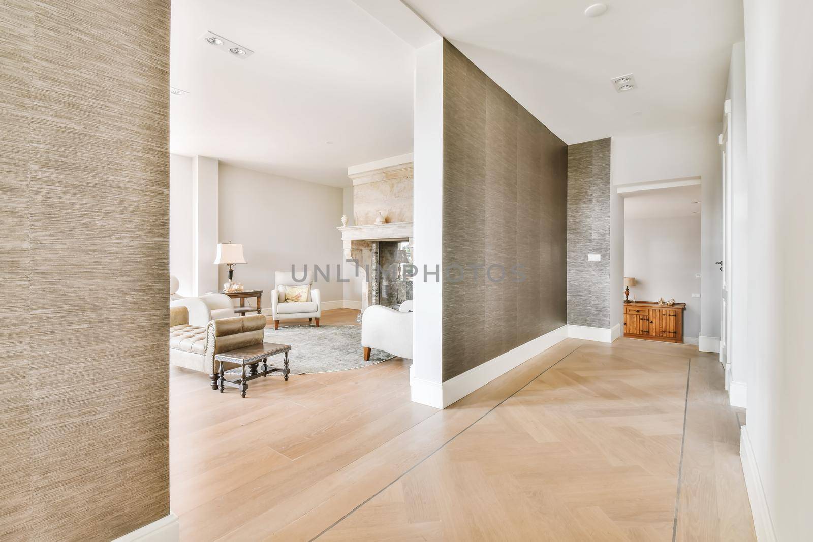 A wide corridor covered with brown wallpaper and an arch leading to the living room