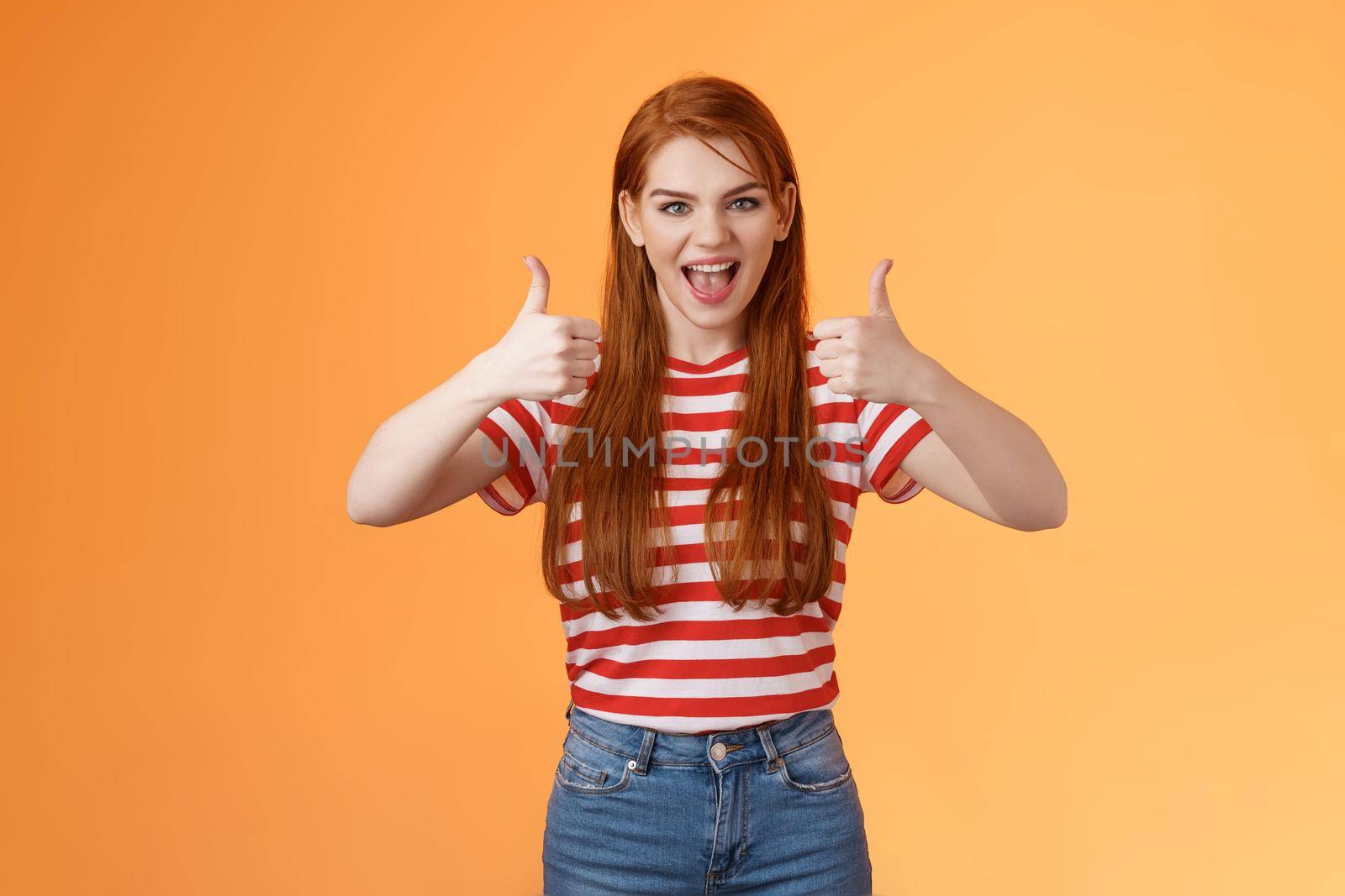 Sassy rebellious wild redhead cool girl having fun adore awesome party, show satisfactory gesture, thumb-up smiling say yeah joyfully, enjoy cool event, having fun, like idea, orange background.