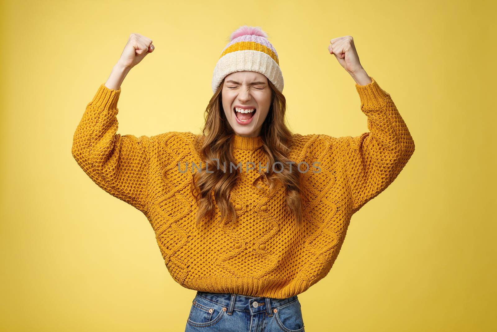 Relieved attractive fashionable university female student yelling proudly raise clenched fists victory cheer gesture celebrating win successful achievement accomplishment goal, yellow background.