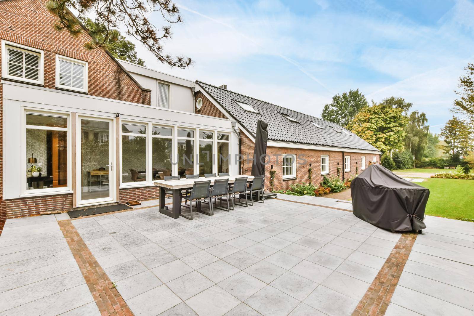 The facade of a one-story brick house with a green fresh lawn in front of the house