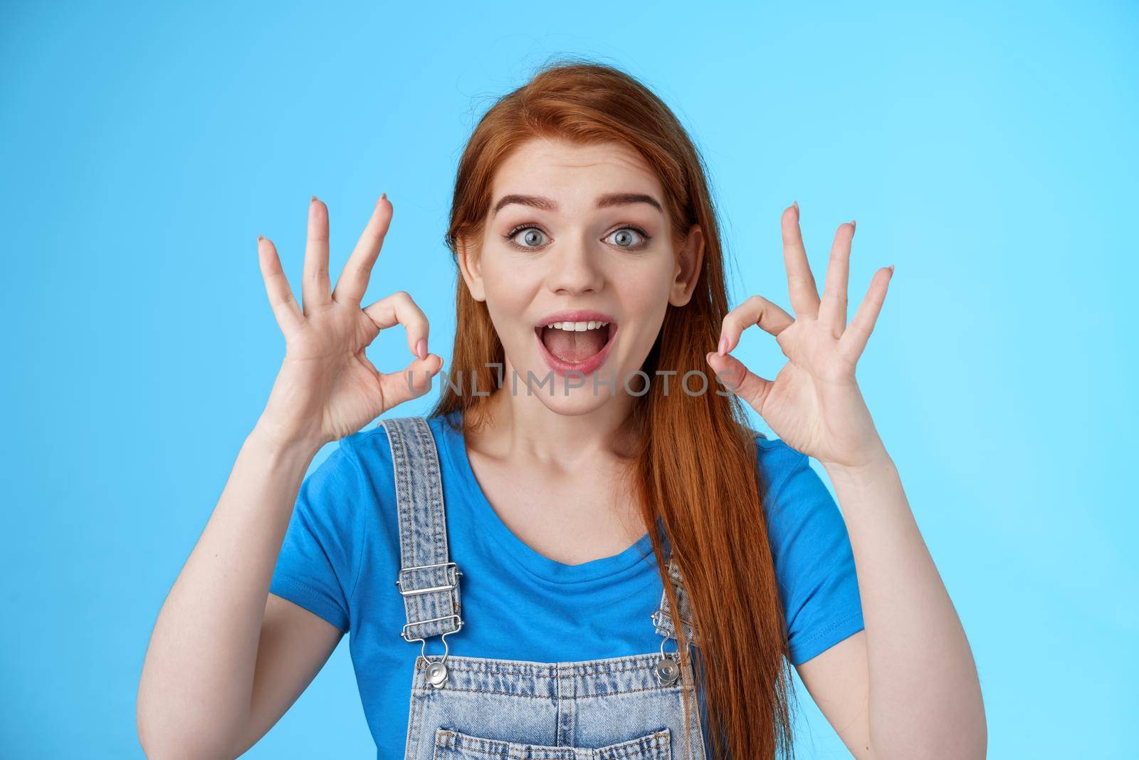 Excellent choice. Redhead female friend approve awesome idea, support accept good purshace, show okay ok confirmation gesture, smiling judging, give positive feedback, stand satisfied blue background by Benzoix