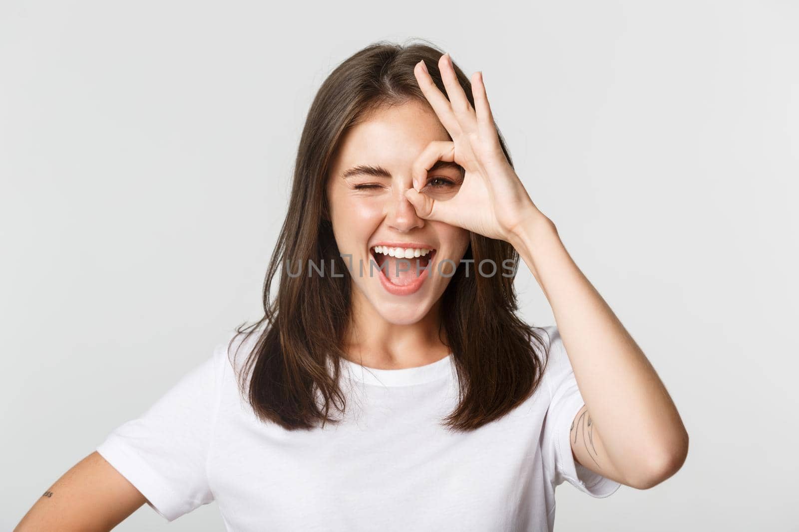 Cheerful attractive girl smiling and showing okay gesture, winking excited.