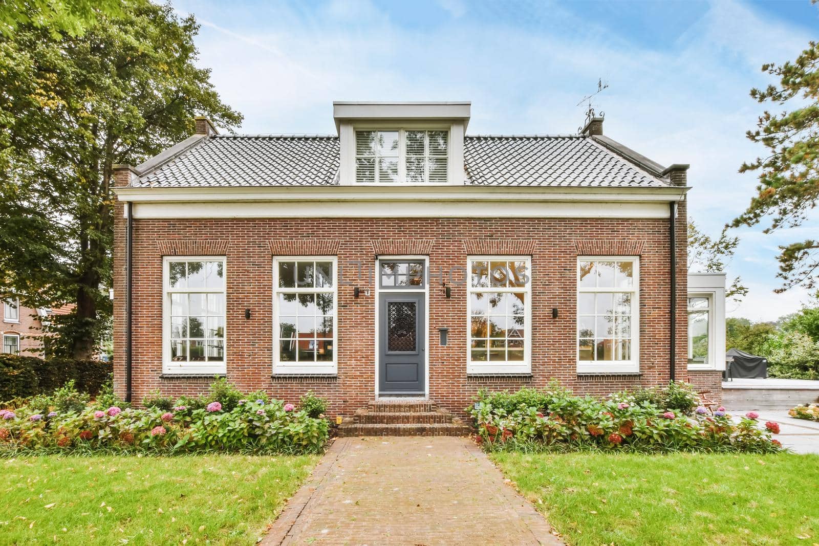 View of an on-storey brick house with greenery on the street