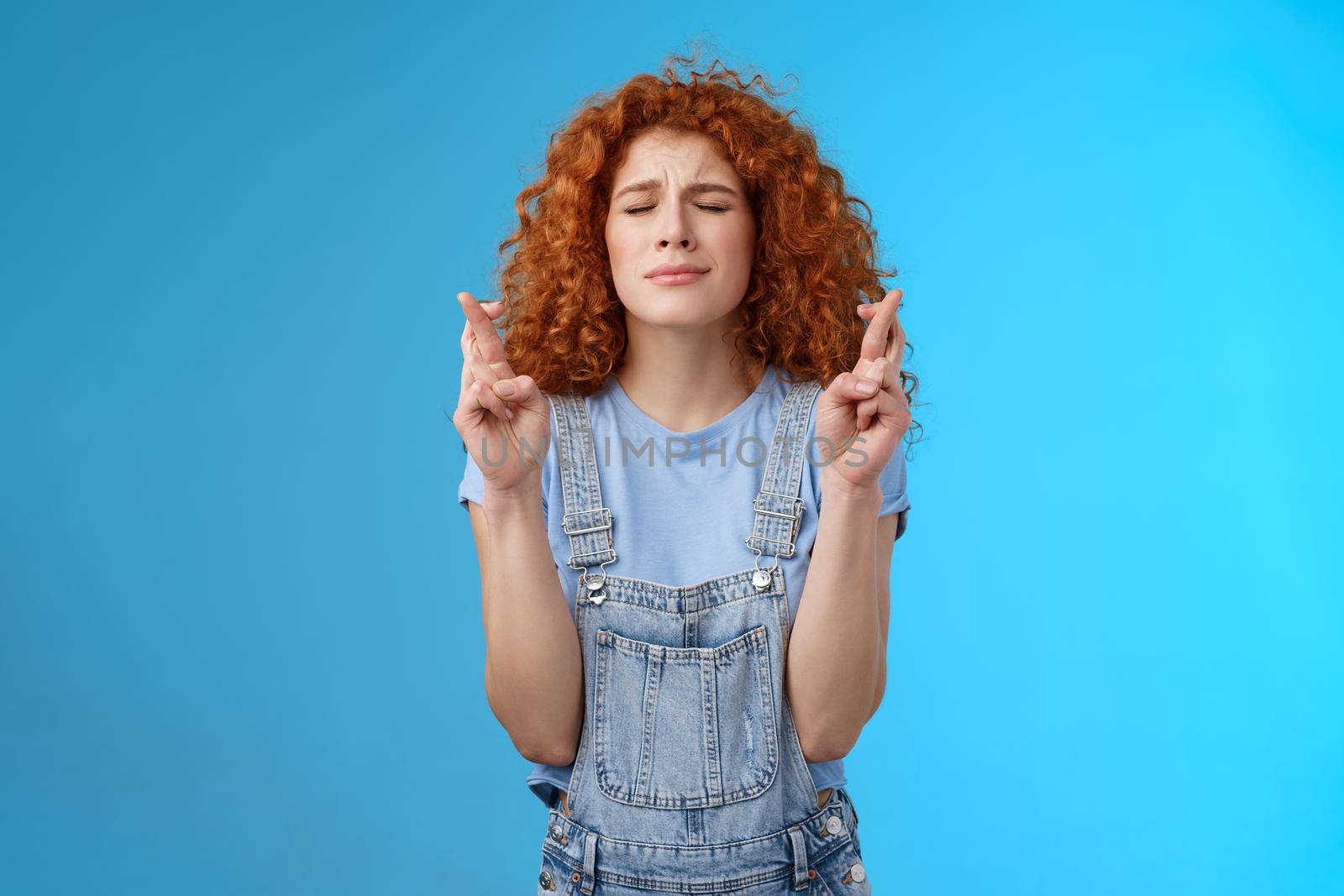 Intense nervous attractive redhead curly-haired hopeful focused girl praying supplicating asking god make dream come true cross fingers good luck anticipating important news wanna wish fulfill.