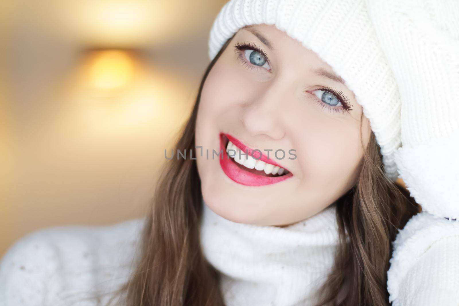 Christmas, people and winter holiday concept. Happy smiling woman wearing white knitted hat as closeup face xmas portrait.