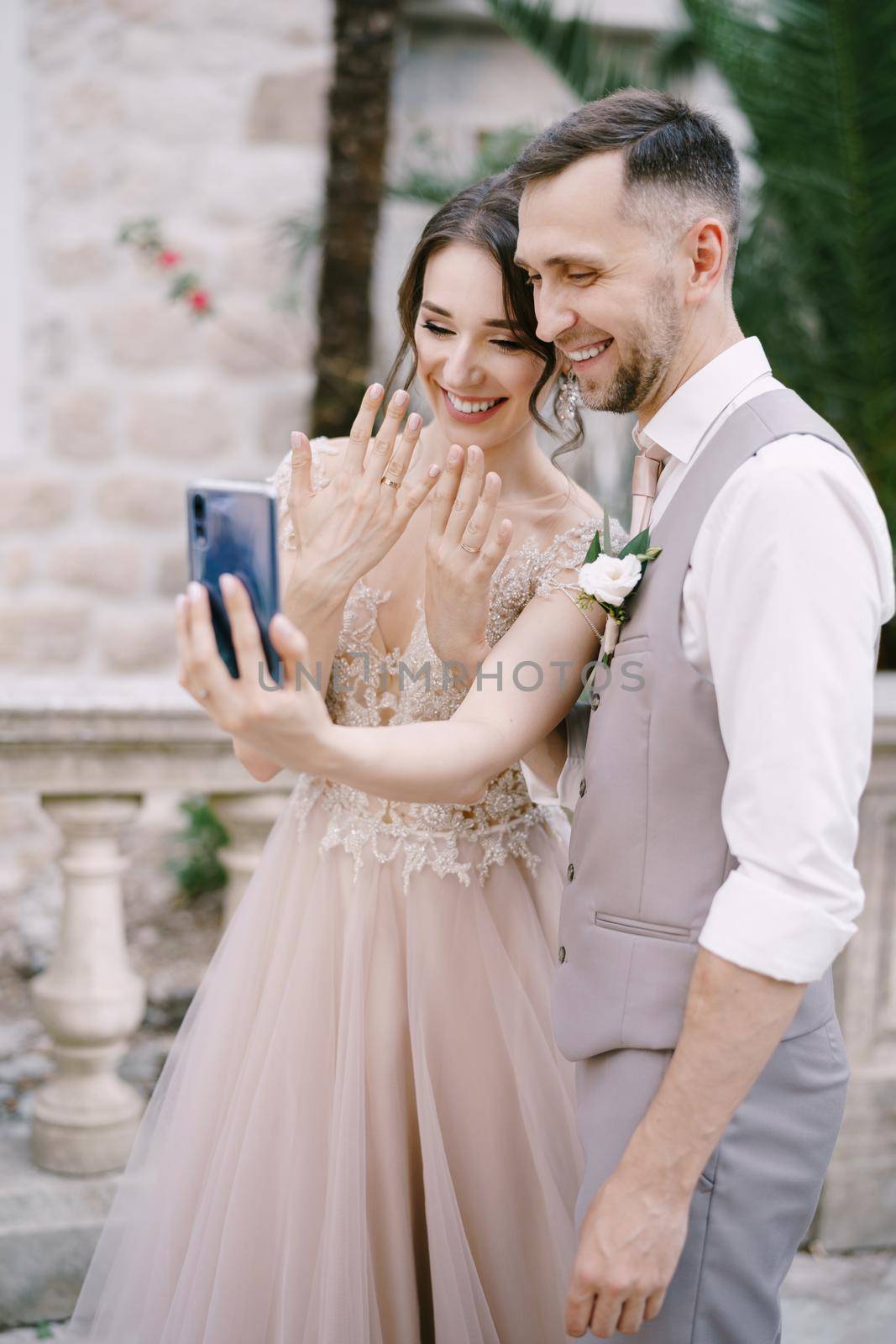 Bride and groom take a selfie with rings on their fingers on a smartphone. High quality photo